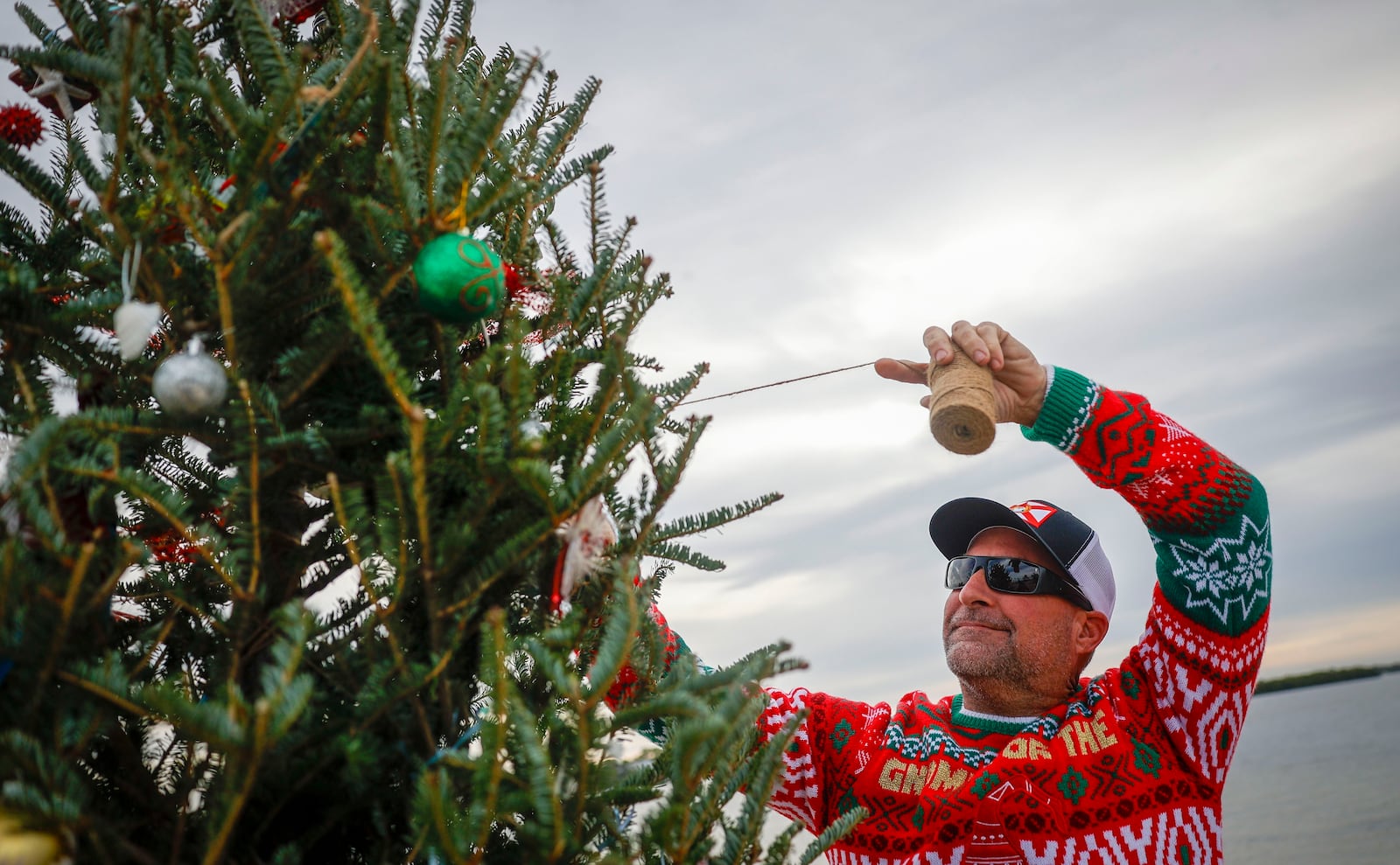 FILE - Mike Womack, 52, puts the final touches on a Christmas tree as he has done for years prior for local residents to enjoy along Sunset Beach, Dec. 24, 2023, in Tarpon Springs, Fla. (Chris Urso/Tampa Bay Times via AP, File)