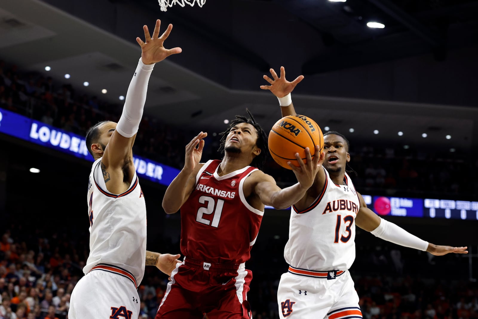 Arkansas guard D.J. Wagner (21) puts up a shot around Auburn forward Johni Broome and guard Miles Kelly (13) during the first half of an NCAA college basketball game, Wednesday, Feb. 19, 2025, in Auburn, Ala. (AP Photo/Butch Dill)