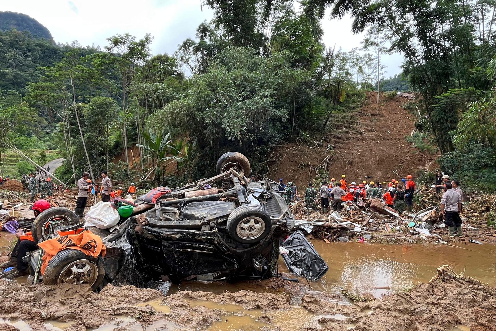 Rescuers search for victims as the wreckage of a car rests in the mud in an area affected by a landslide following a flash flood that killed multiple people in Pekalongan, Central Java, Indonesia, Thursday, Jan. 23, 2025. (AP Photo/Janaki DM)