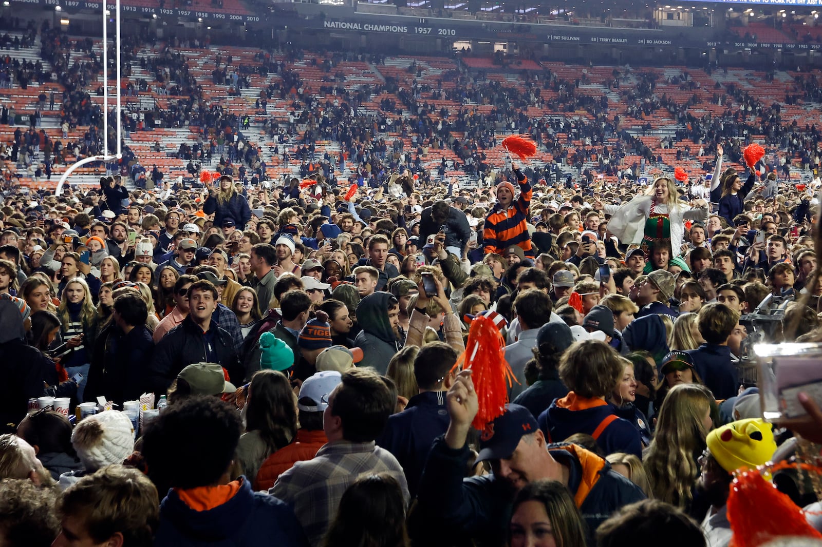 Auburn fans storm the field after defeating Texas A&M during the fourth overtime of an NCAA college football game, Saturday, Nov. 23, 2024, in Auburn, Ala. (AP Photo/Butch Dill)