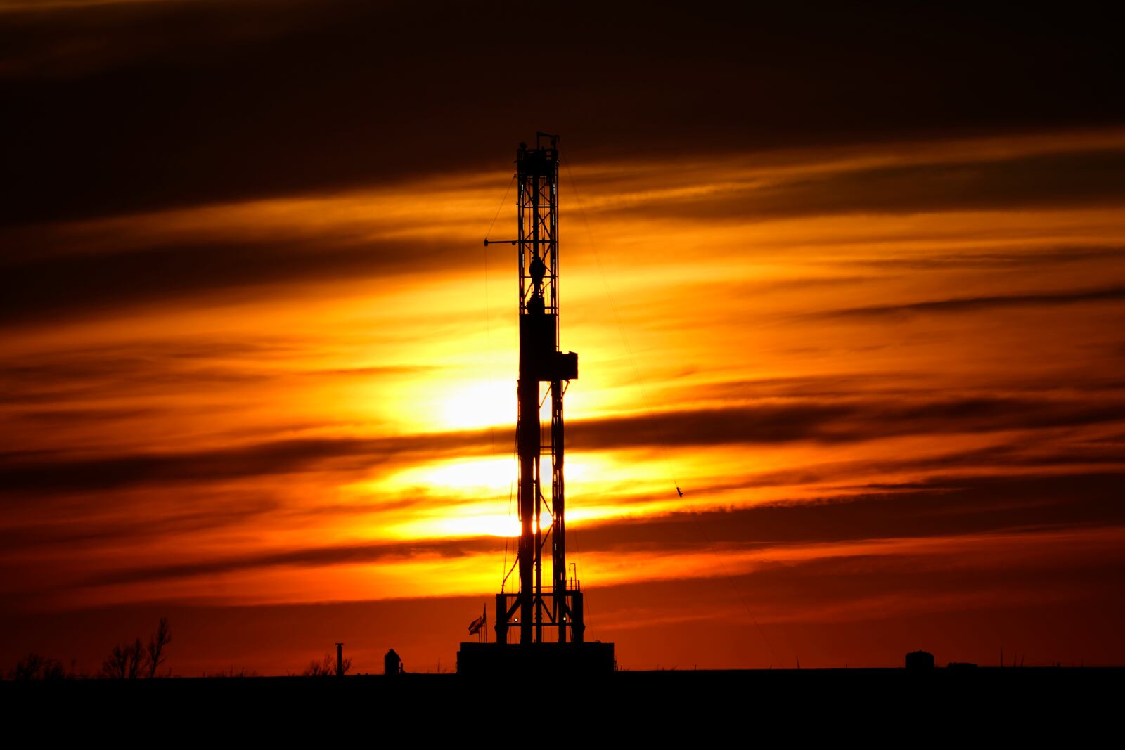 FILE - An oil drilling rig is pictured at sunset, Monday, March 7, 2022, in El Reno, Okla. A federal appeals court in New Orleans hears arguments Tuesday, May 10, 2022, about whether President Joe Biden legally suspended new oil and gas lease sales because of climate change worries. (AP Photo/Sue Ogrocki, File)