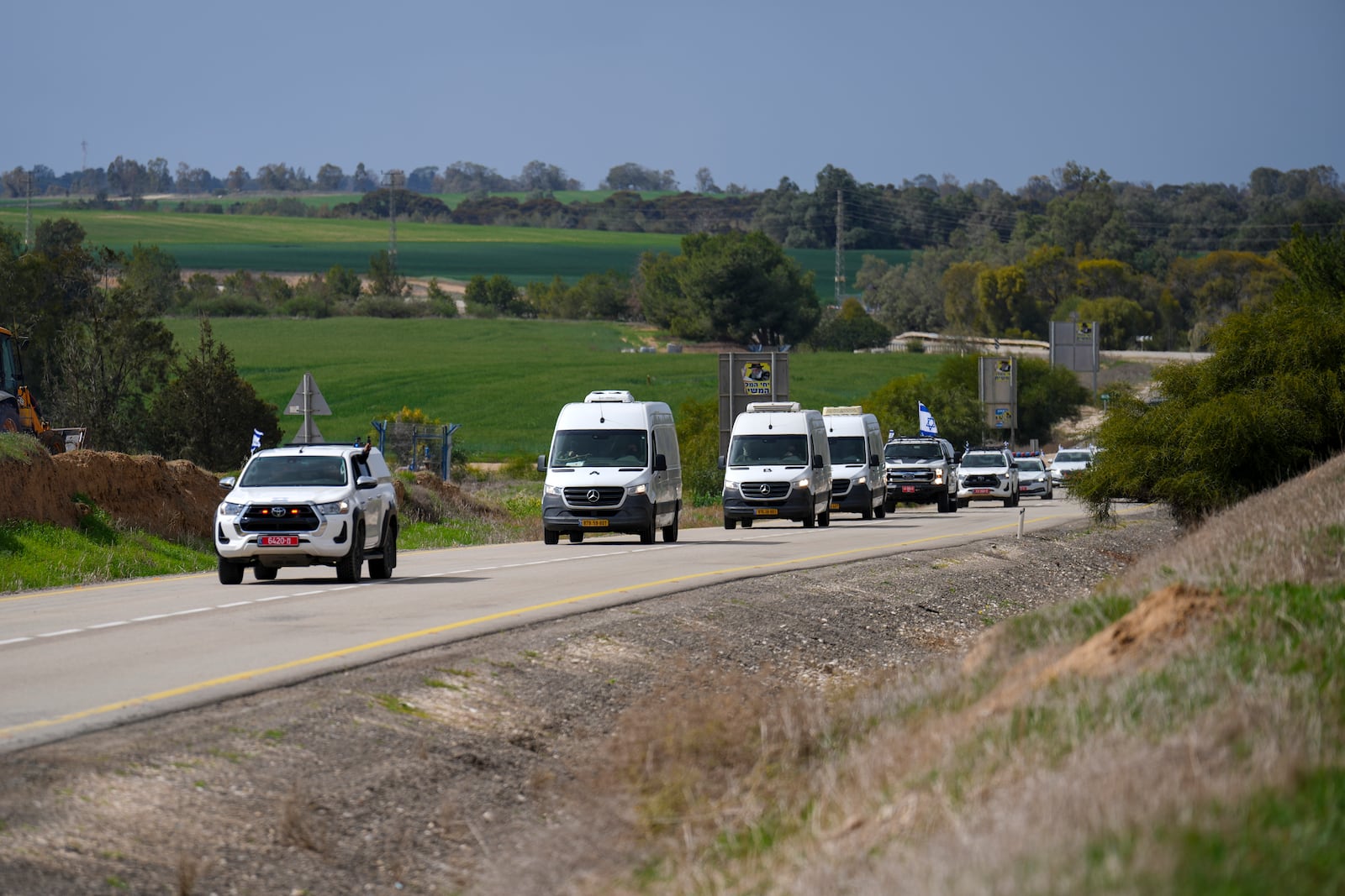 A convoy carrying the coffins containing the bodies of four Israeli hostages, including a mother and her two children, handed over by Palestinian militant groups in Gaza, drives by a road near Kibbutz Reim, southern Israel, Thursday, Feb. 20, 2025.(AP Photo/Ariel Schalit)