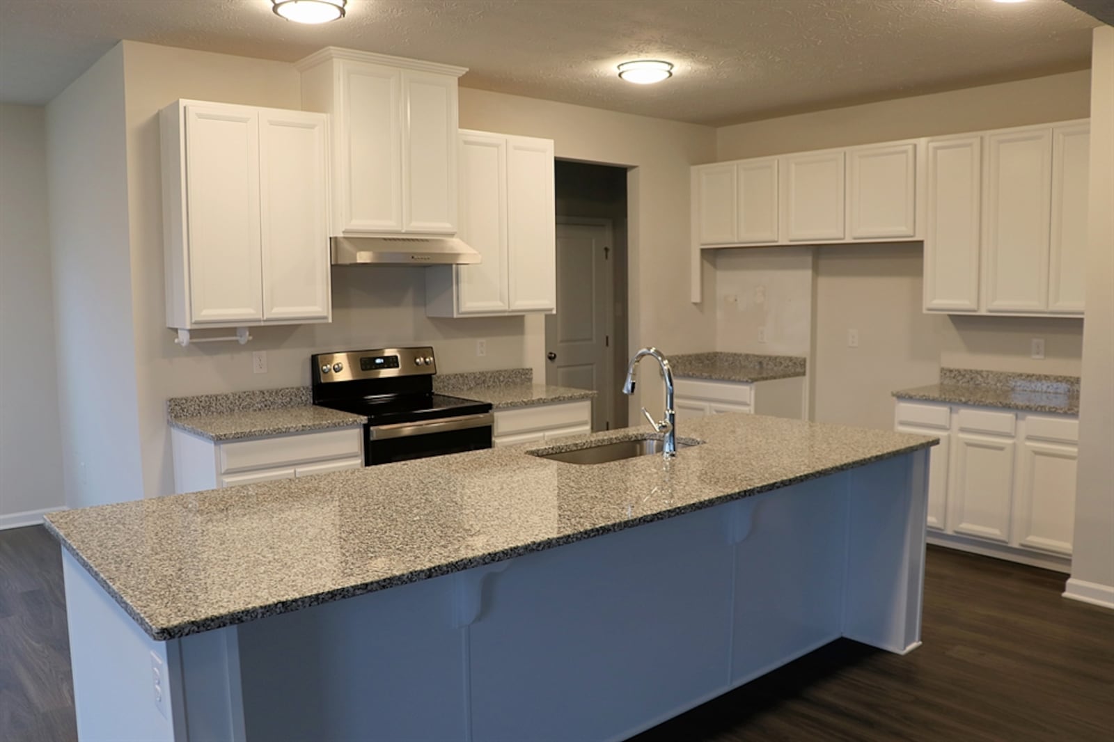 A large island with extended counter and single sink offers breakfast bar seating up to six and provides preparation space for the kitchen.