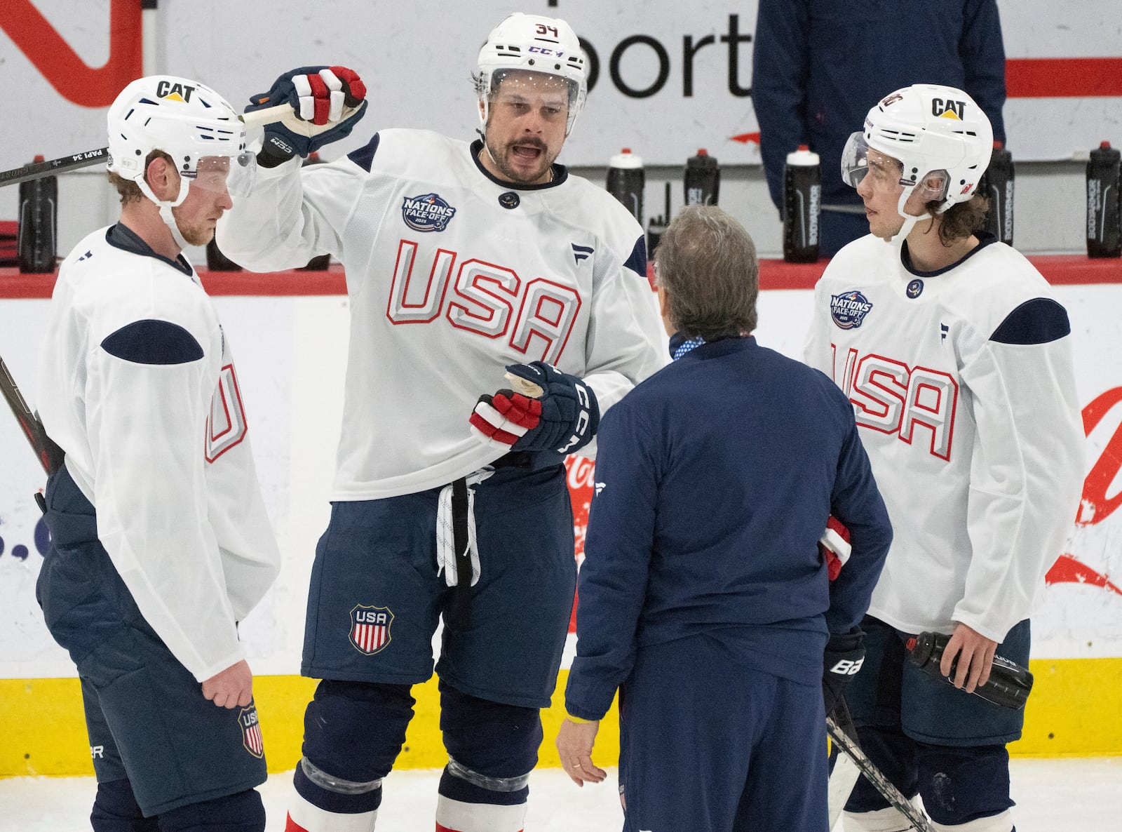 United States' Austin Matthews, second from left, Jack Eichel, left, and Jack Hughes, right, speak with coaching staff during during a 4 Nations Face-Off hockey practice in Brossard, Quebec, Monday, Feb. 10, 2025. (Christinne Muschi/The Canadian Press via AP)