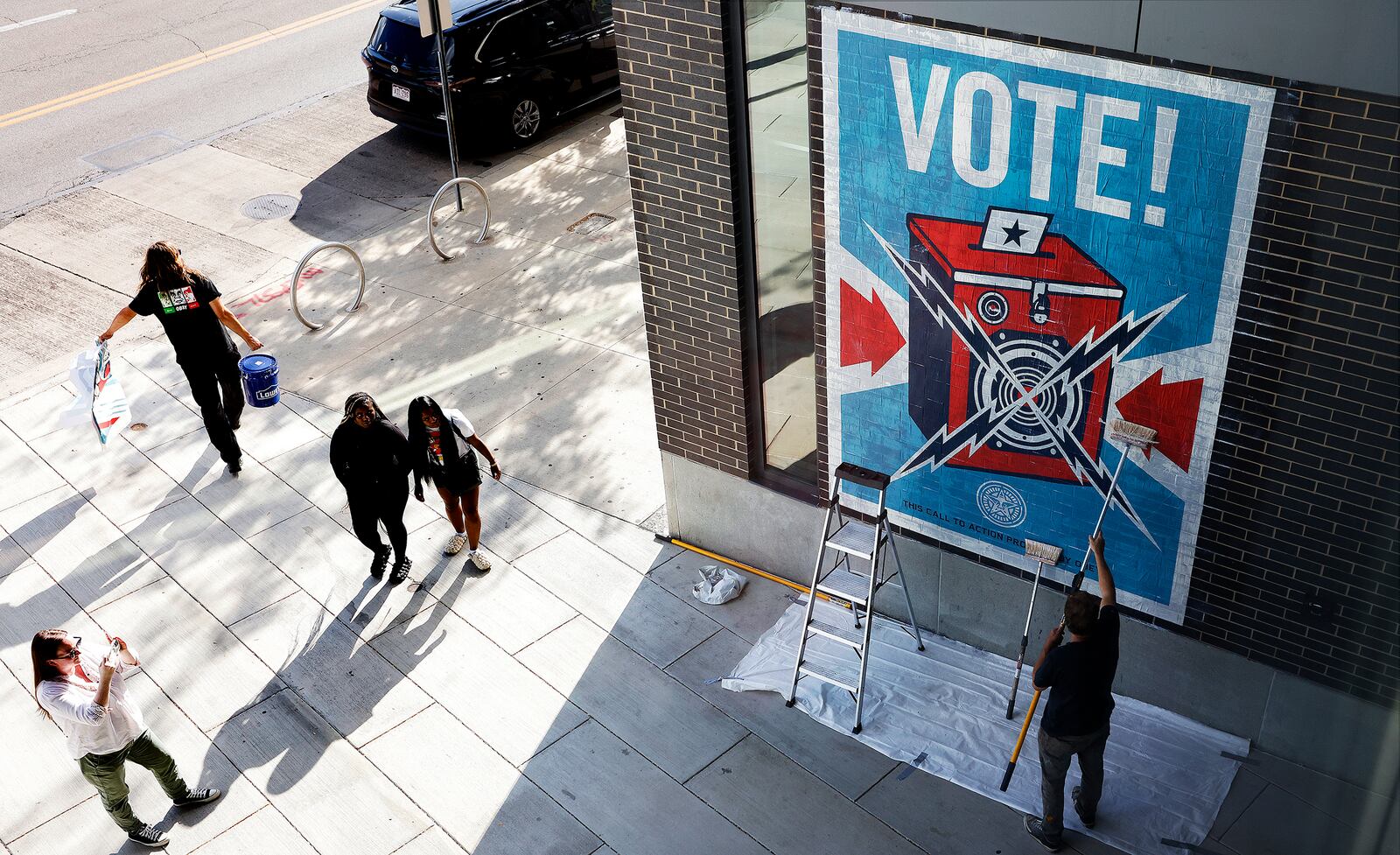 Muralist Shepard Fairey, places a mural Wednesday 18, 2024 on the Dayton Metro Library Downtown. MARSHALL GORBY\STAFF