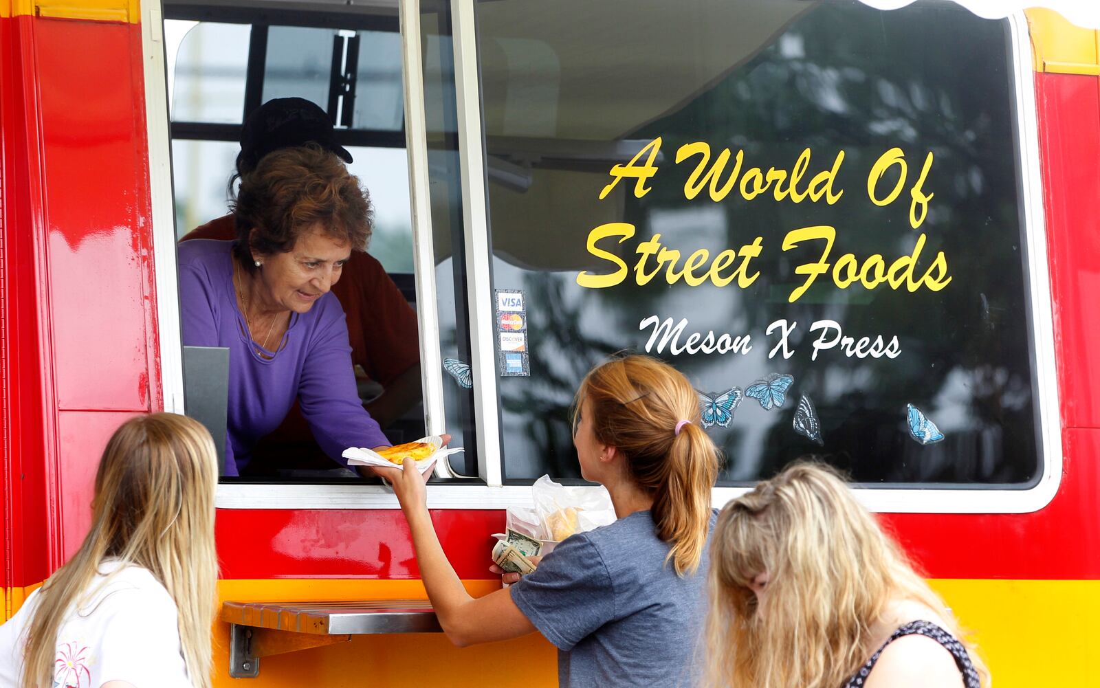 Gloria Castro, an owner of El Meson restaurant, serves food from their food truck.   LISA POWELL / STAFF