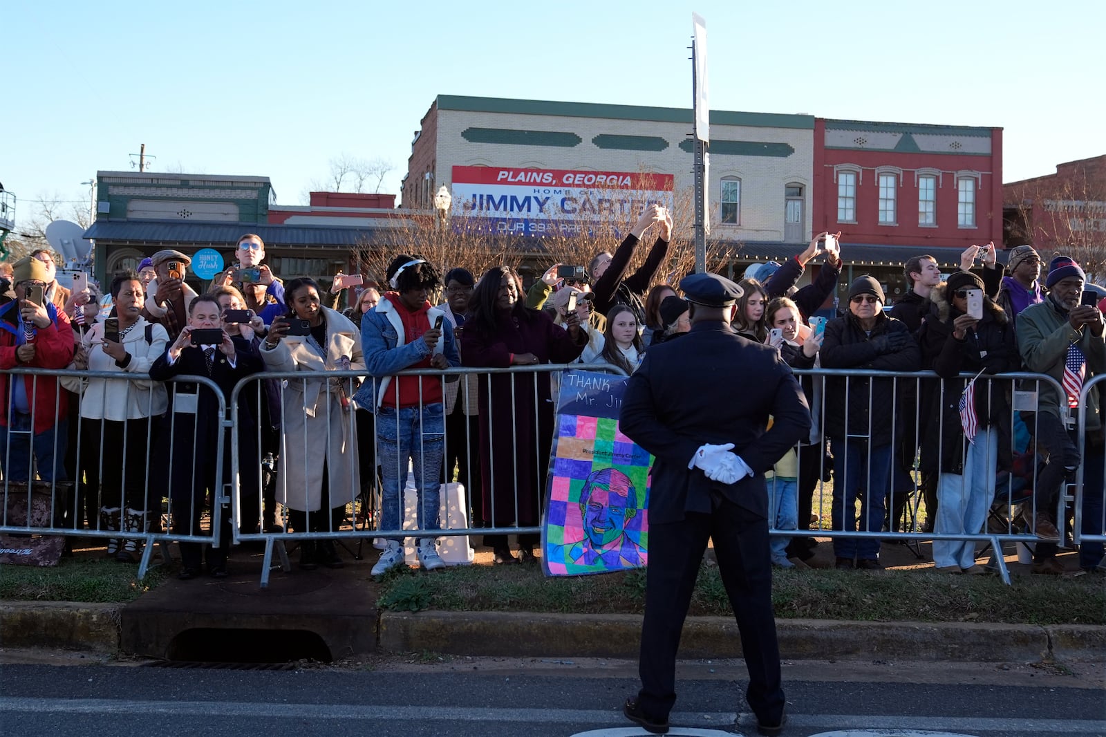 People watch as the hearse containing the flag-draped casket of former President Jimmy Carter passes through downtown Plains, Ga., toward Maranatha Baptist Church for a funeral service Thursday, Jan. 9, 2025. (AP Photo/Alex Brandon, Pool)