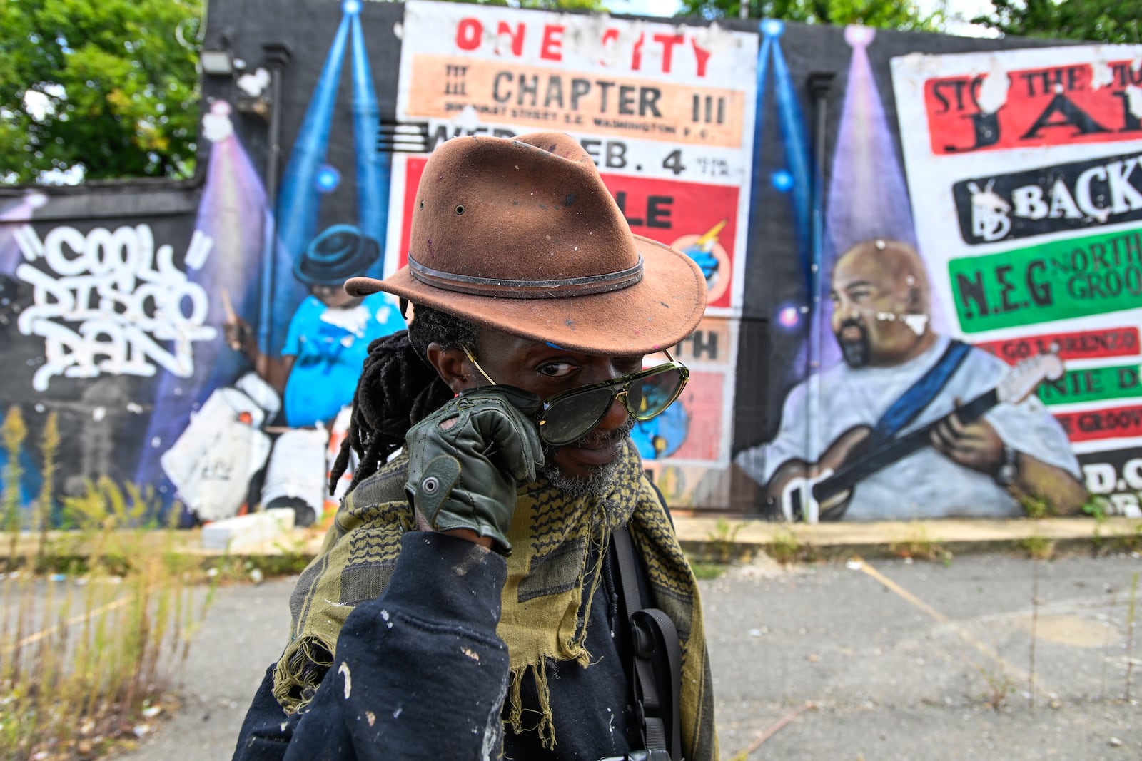 Mural artist Eric B. Ricks poses for a portrait in front of a mural that he oversaw and instructed young artist to paint in 2017 , Monday, Sept. 16, 2024, in Washington. (AP Photo/John McDonnell)