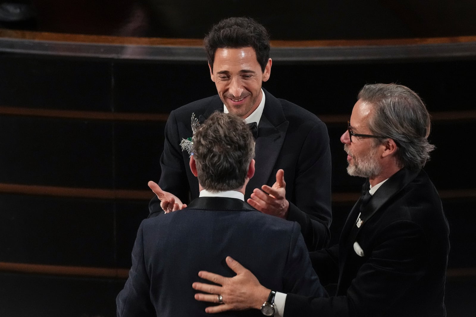 Adrien Brody, top, and Guy Pearce, right, congratulates Lol Crawley, front, for winning the award for best cinematography for "The Brutalist" during the Oscars on Sunday, March 2, 2025, at the Dolby Theatre in Los Angeles. (AP Photo/Chris Pizzello)