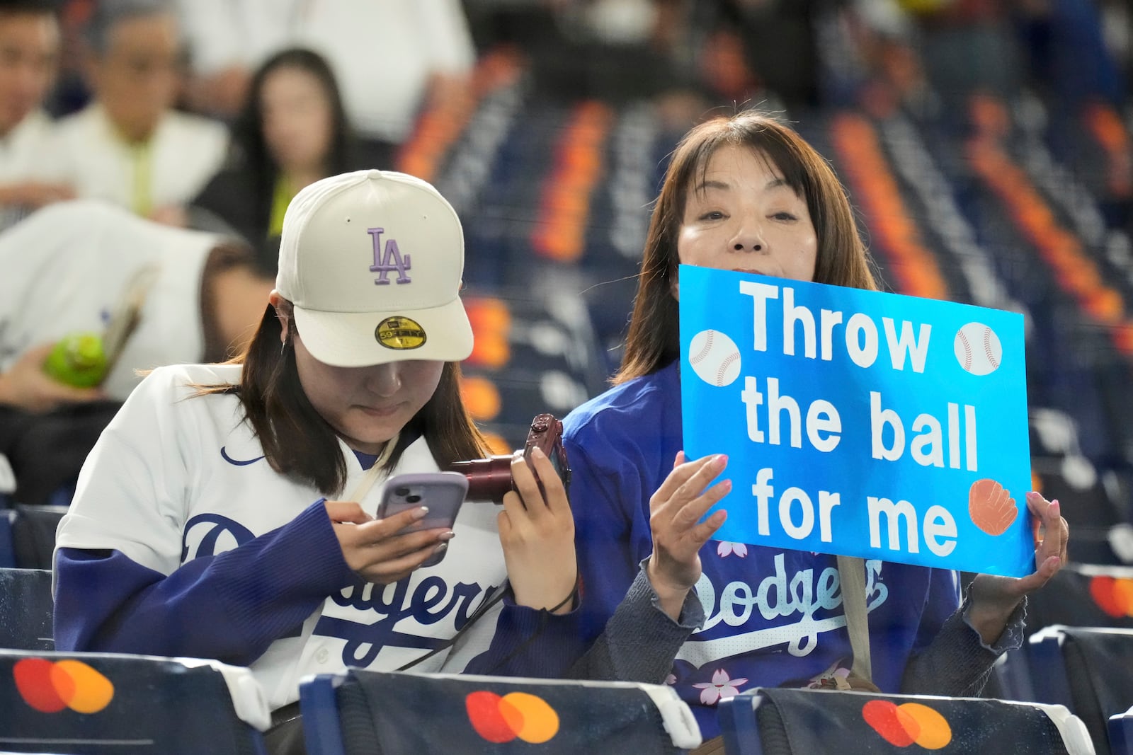 A fan holds a sign as they wait for the start of an MLB Japan Series baseball game between the Los Angeles Dodgers and Chicago Cubs in Tokyo, Japan, Tuesday, March 18, 2025. (AP Photo/Eugene Hoshiko)