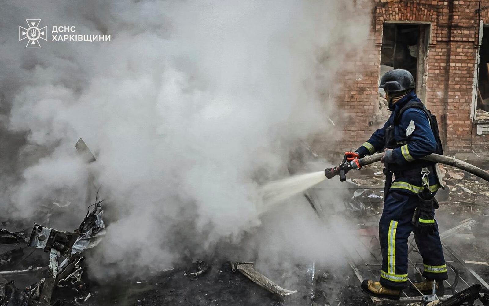 In this photo provided by the Ukrainian Emergency Services on Nov. 25, 2024, a rescue worker puts out a fire of a burned car in the yard of an apartment building damaged by a Russian strike on a residential neighbourhood in Kharkiv, Ukraine. (Ukrainian Emergency Service via AP)