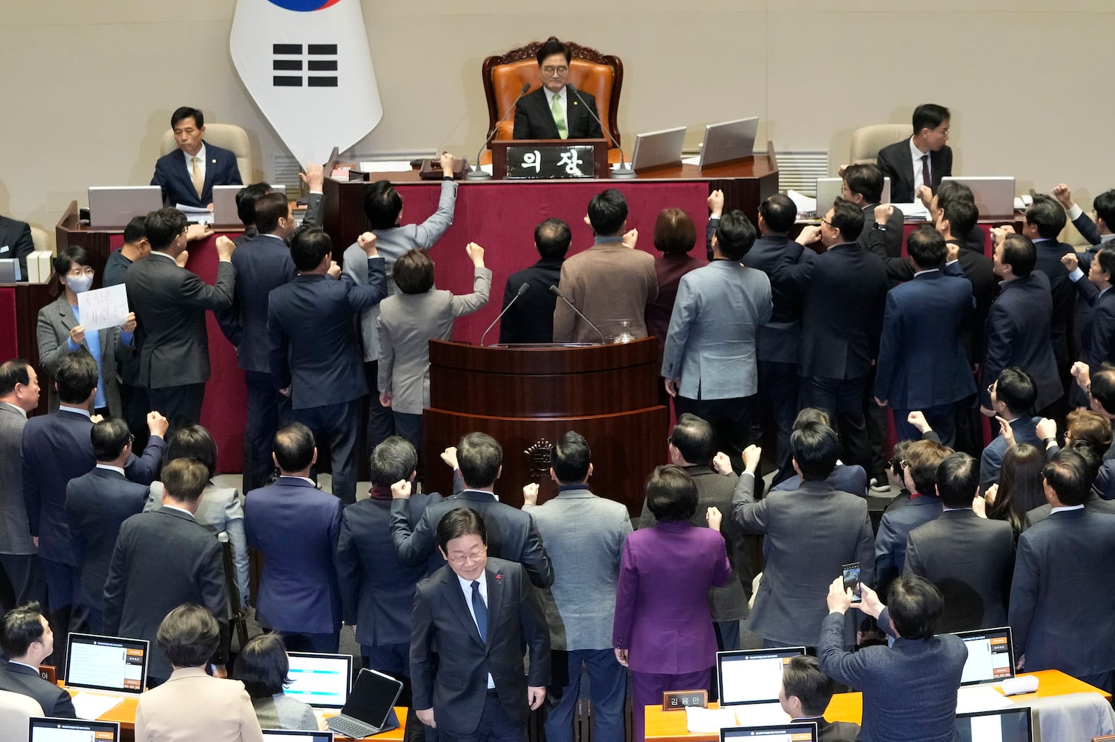 South Korea's opposition Democratic Party leader Lee Jae-myung, bottom center, walks past lawmakers of the ruling People Power Party protesting to South Korea's National Assembly Speaker Woo Won Shik, top center, during a plenary session for the impeachment motion against South Korean acting President Han Duck-soo at the National Assembly in Seoul, South Korea, Friday Dec. 27, 2024. (AP Photo/Ahn Young-joon)