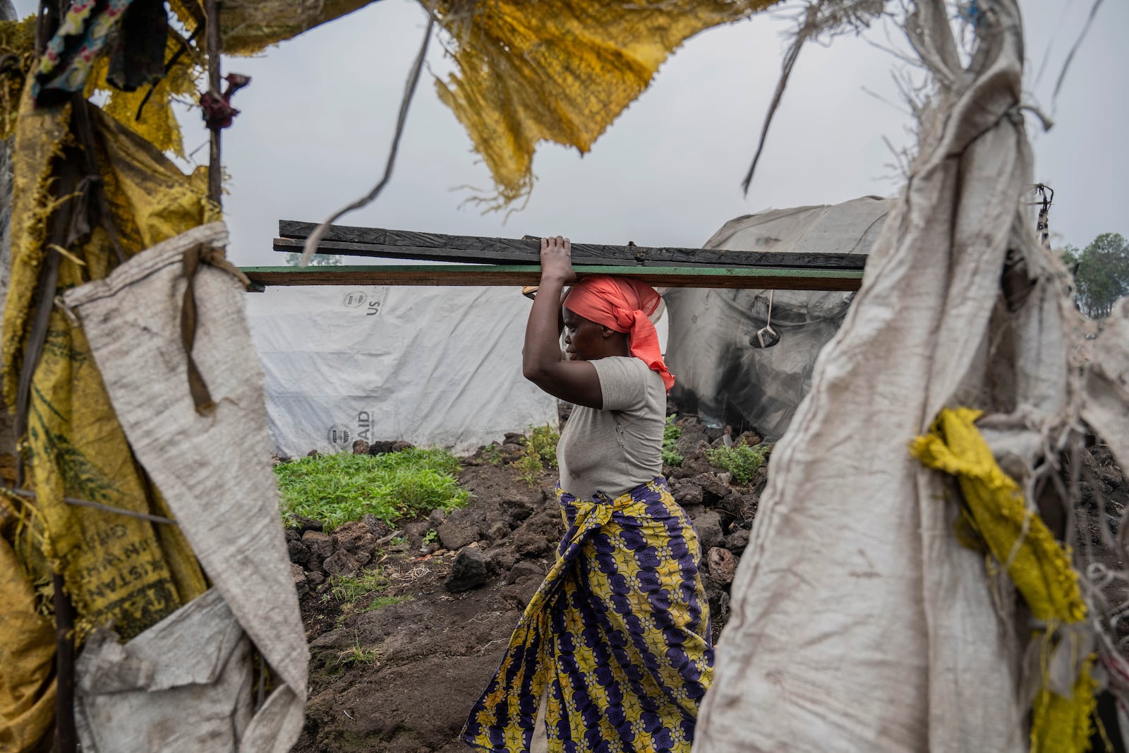 A woman displaced by the fighting between M23 rebels and government soldiers leaves the camp following an instruction by M23 rebels in Goma, Democratic Republic of the Congo, Tuesday, Feb. 11, 2025. (AP Photo/Moses Sawasawa)