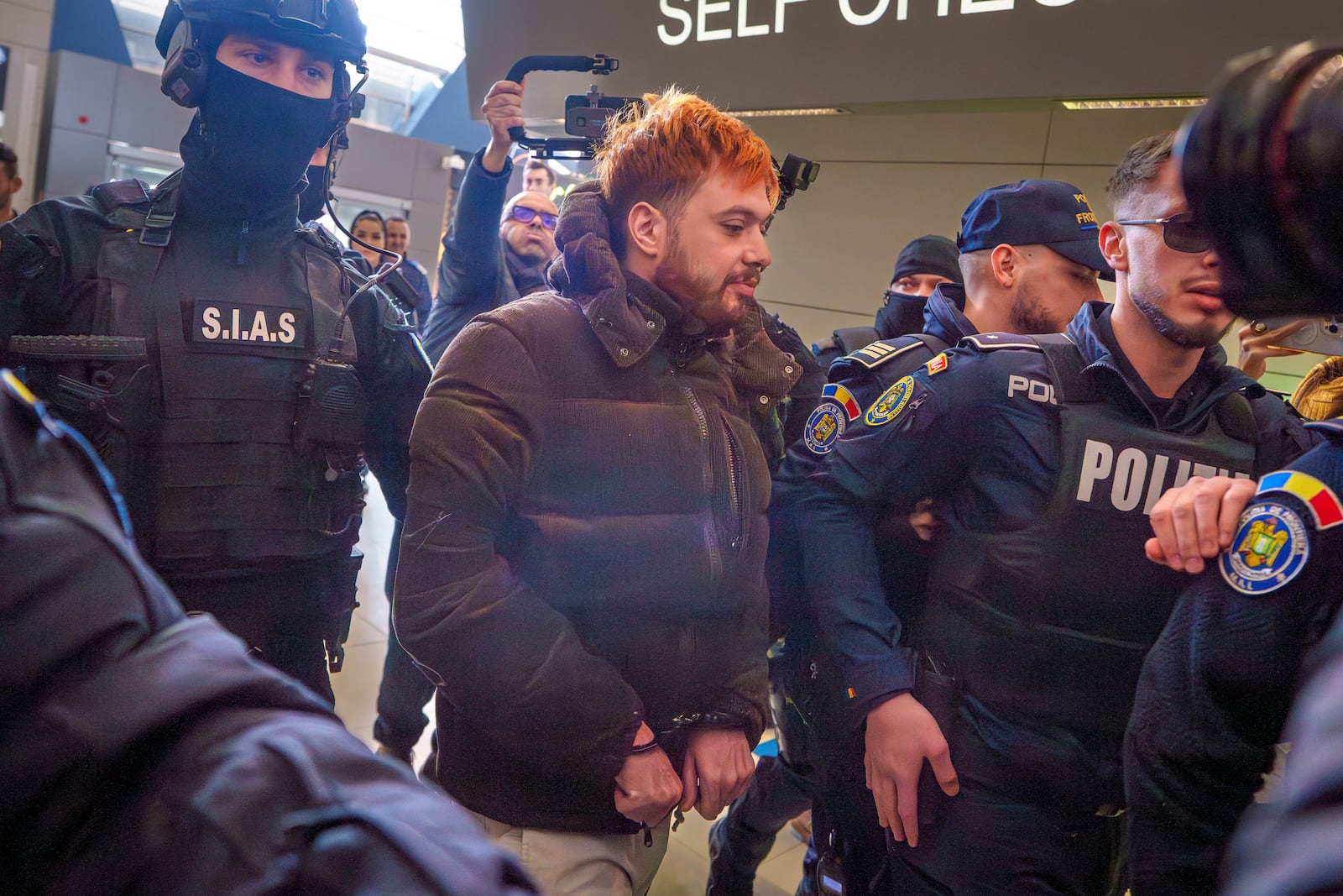 Mohamed Amra, nicknamed ''The Fly", is escorted by armed police officers at the Henri Coanda international airport in Otopeni, Romania, Tuesday, Feb. 25, 2025, before being extradited to France. (AP Photo/Vadim Ghirda)