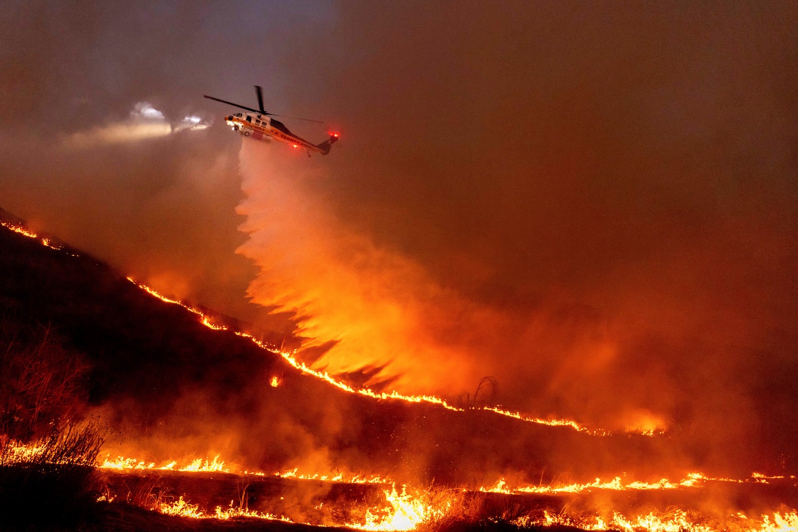 Water is dropped by helicopter on the Kenneth Fire in the West Hills section of Los Angeles, Thursday, Jan. 9, 2025. (AP Photo/Ethan Swope)