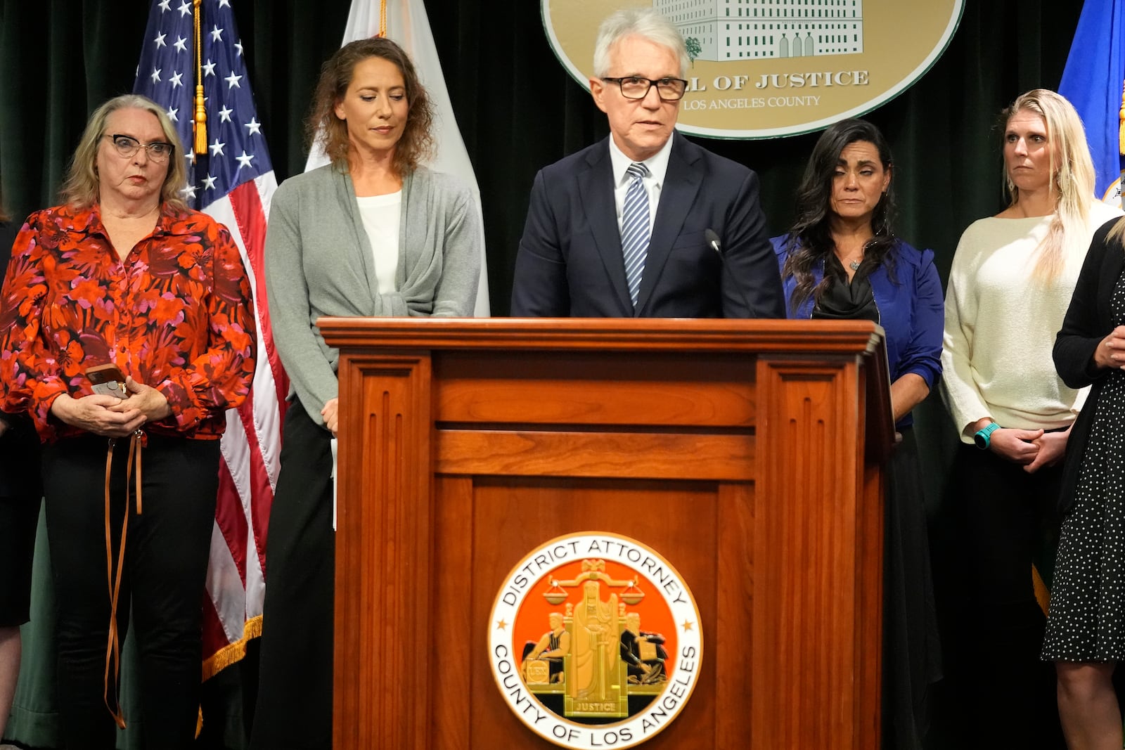 Los Angeles County District Attorney George Gascon, right, flanked by Menedez family members talks during a news conference at the Hall of Justice on Thursday, Oct. 24, 2024, in Los Angeles. (AP Photo/Damian Dovarganes)