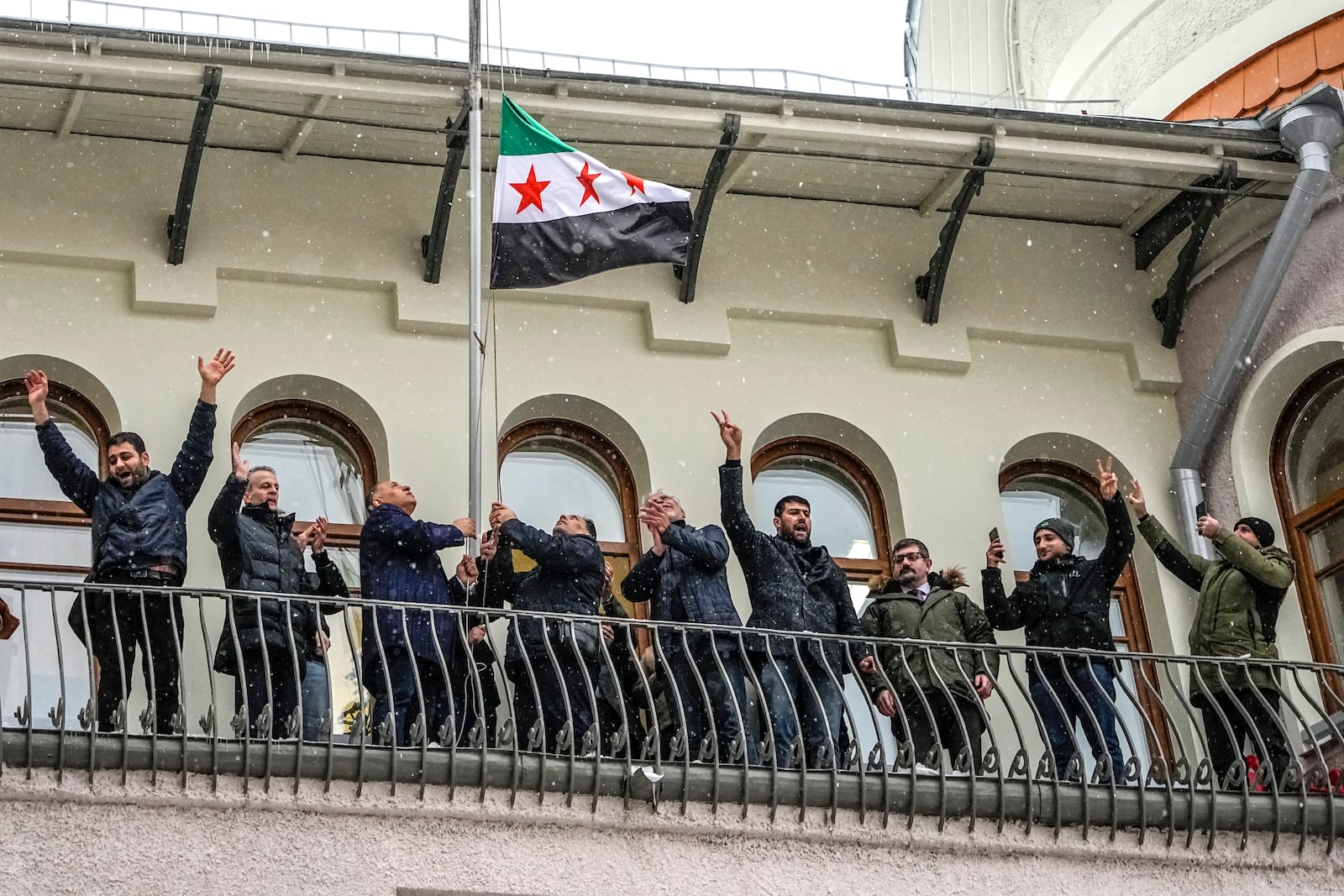 FILE - Members of the Syrian diaspora wave while flying the Syrian opposition flag at the Syrian Embassy, in Moscow, Russia, on Dec. 9, 2024. (AP Photo/Alexander Zemlianichenko, File)