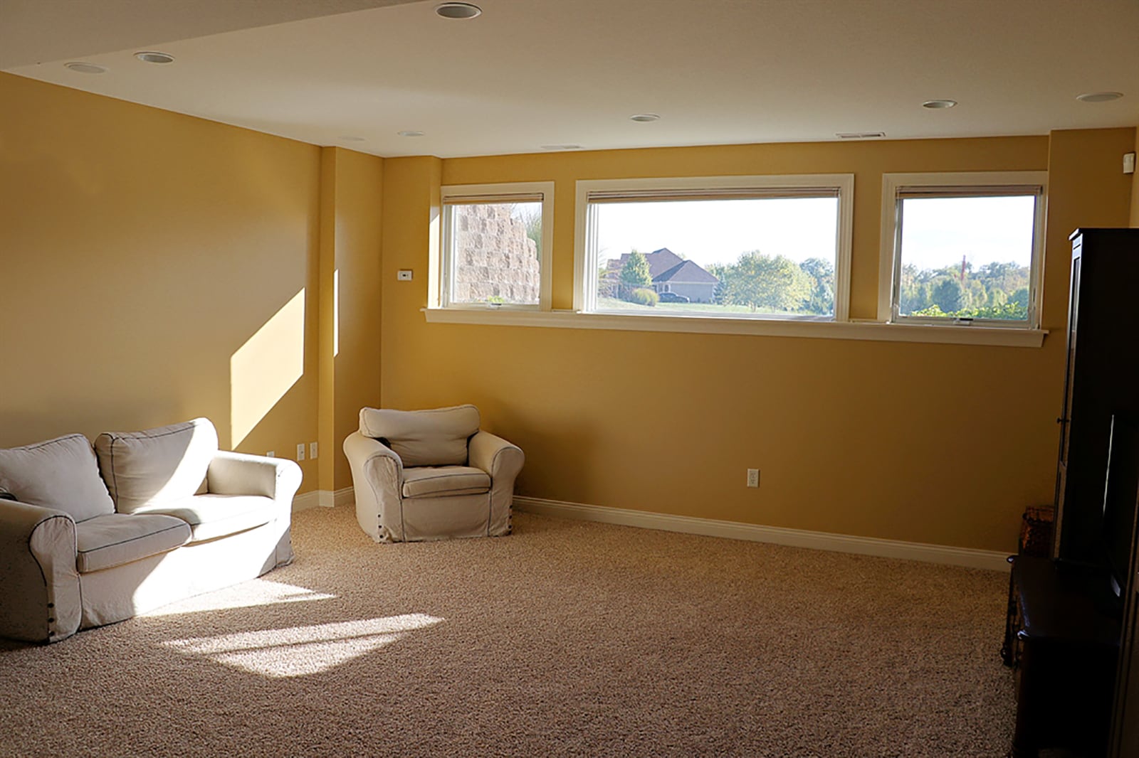 A stairwell opens into the lower-level family room setting with three daylight windows that look out over the pond. Carpeting fills the room, and there are several canister lights. CONTRIBUTED PHOTO BY KATHY TYLER