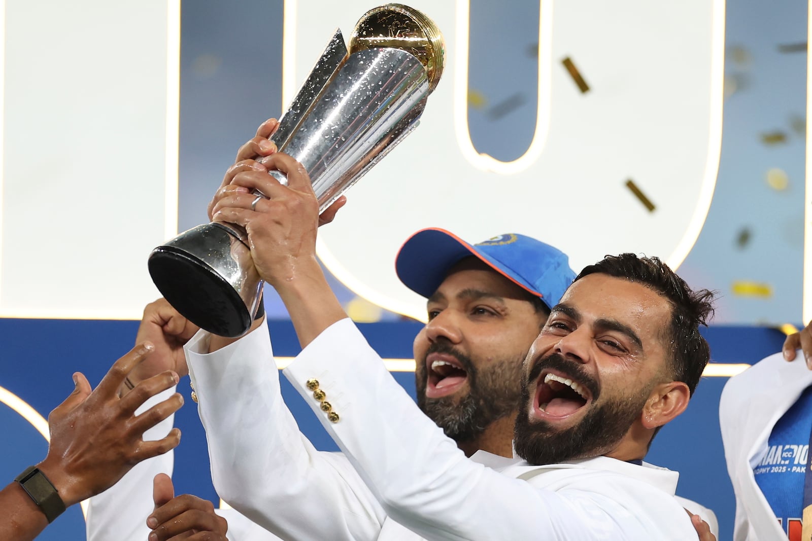 India's Virat Kohli, right, and captain Rohit Sharma celebrate with the winners trophy on the podium after defeating New Zealand in the final cricket match of the ICC Champions Trophy at Dubai International Cricket Stadium in Dubai, United Arab Emirates, Sunday, March 9, 2025. (AP Photo/Christopher Pike)