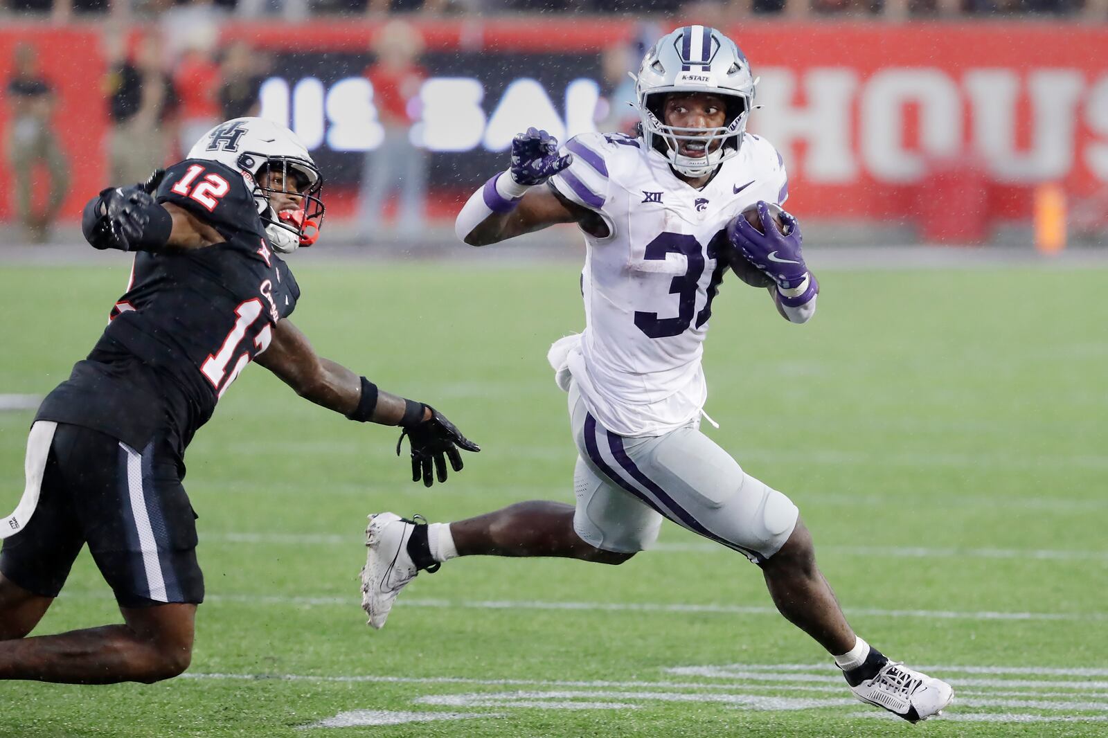 Kansas State running back DJ Giddens, right, makes a gain in front of Houston defensive back Ajani Carter (12) during the second half of an NCAA college football game Saturday, Nov. 2, 2024, in Houston. (AP Photo/Michael Wyke)