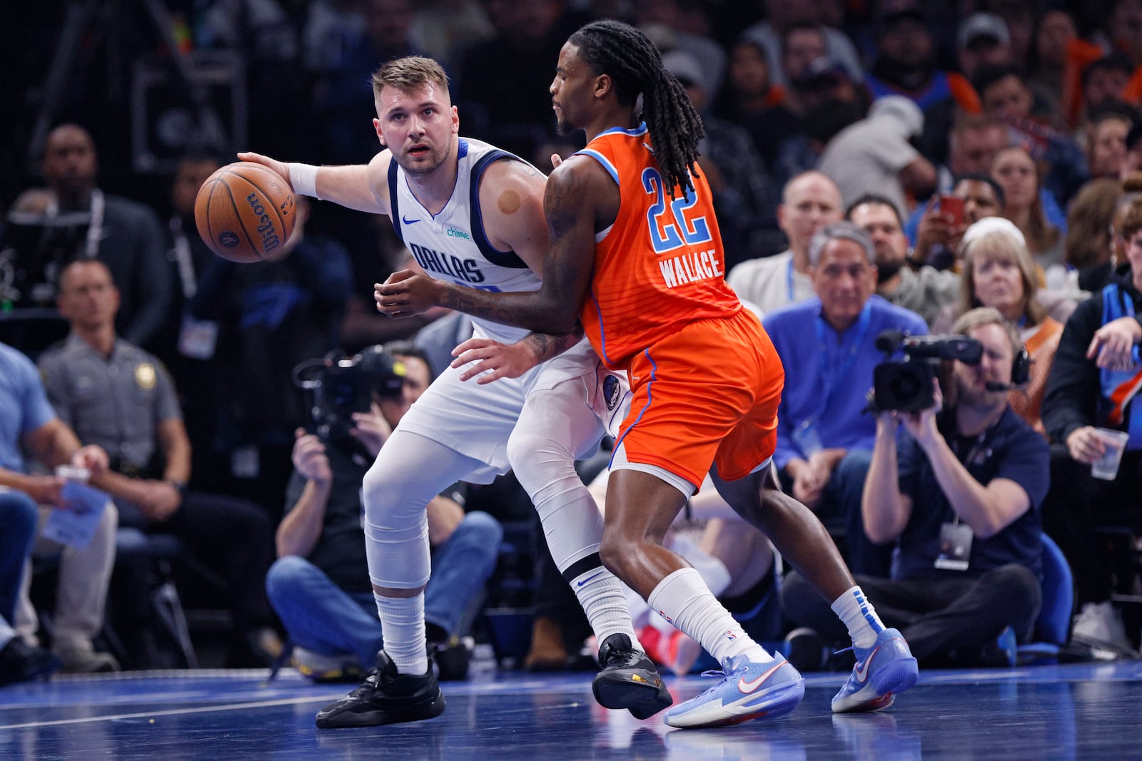 Dallas Mavericks guard Luka Doncic, left, handles the ball as Oklahoma City Thunder guard Cason Wallace (22) defends during the first half of an Emirates NBA Cup basketball game, Tuesday, Dec. 3, 2024, in Oklahoma City. (AP Photo/Nate Billings)