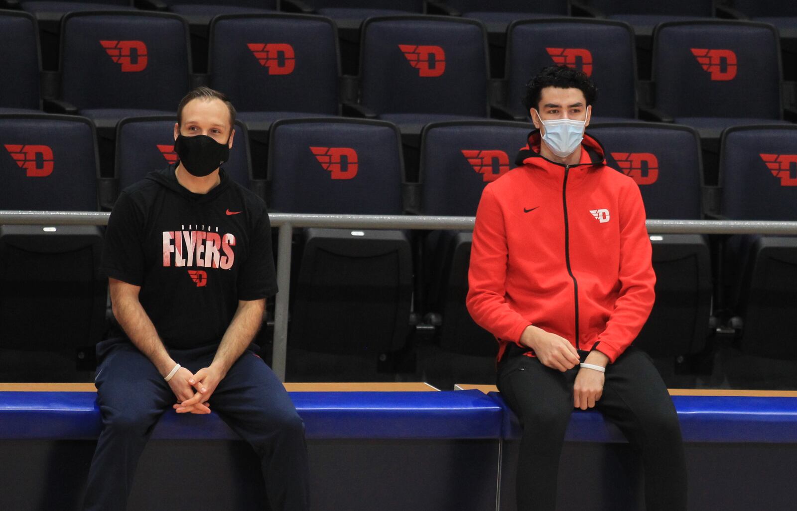 Dayton trainer Casey Cathrall, left, and freshman Mustapha Amzil watch the team warm up on Saturday, Dec. 19, 2020, before a game against Mississippi at UD Arena. David Jablonski/Staff