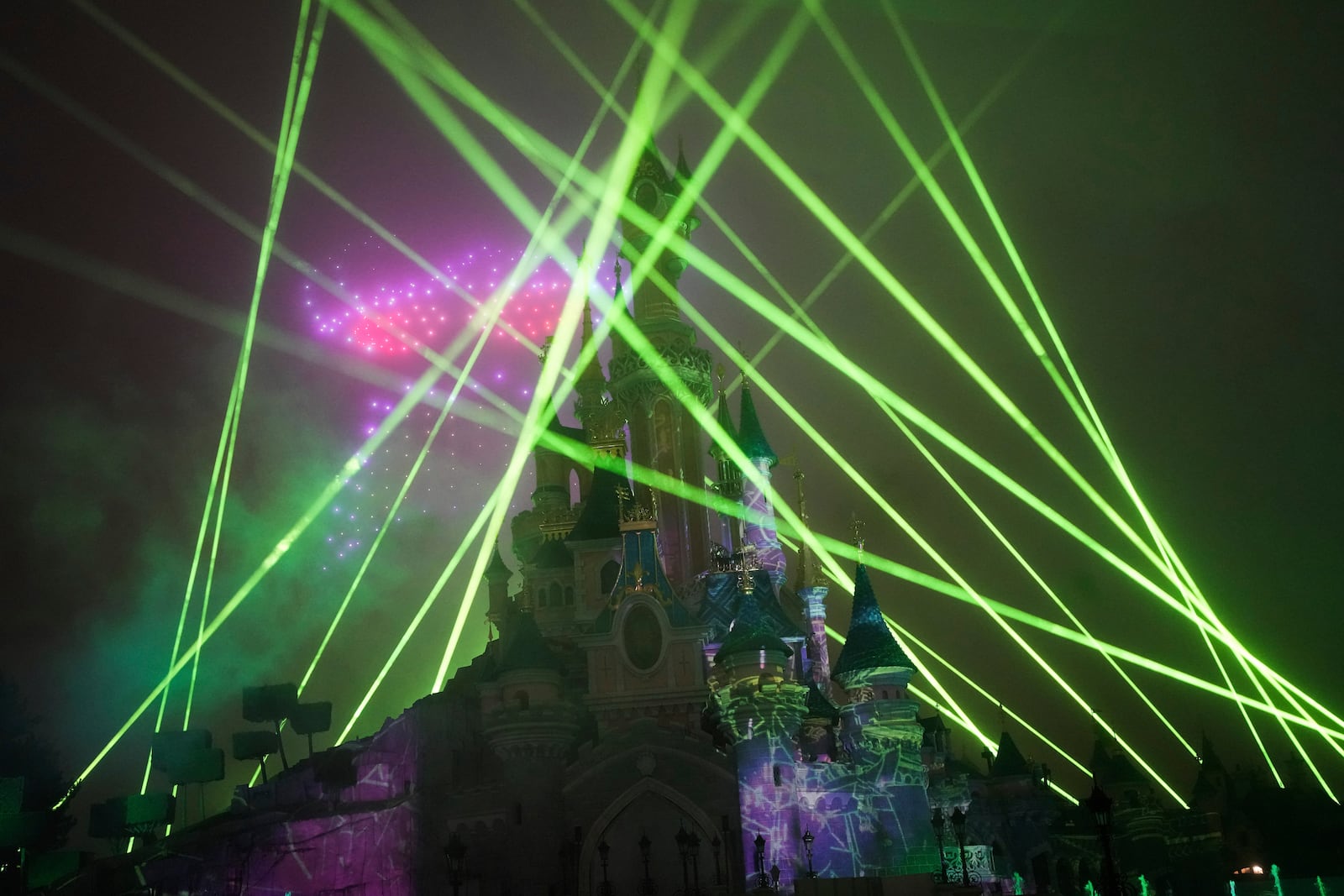 A light show is projected on the castle of Sleeping Beauty as fireworks explode in Disneyland, in Marne-la-Vallee, east of Paris, Friday Jan. 17, 2025. (AP Photo/Thibault Camus)