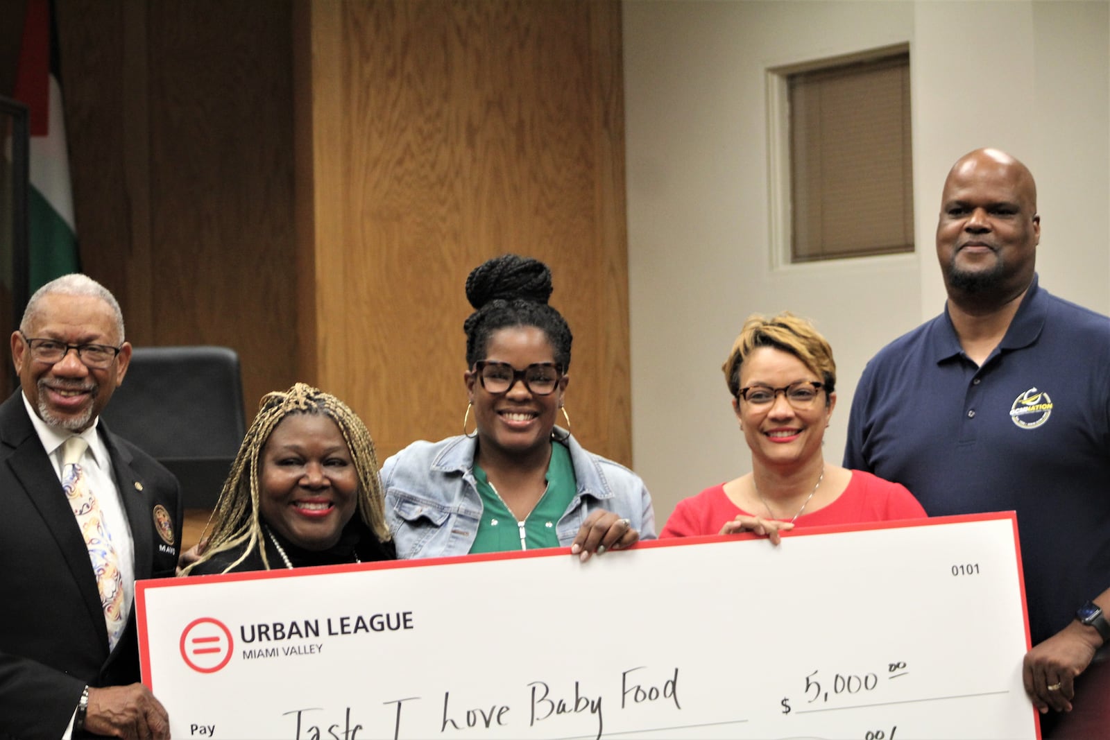 Dayton Mayor Jeffrey Mims Jr. and Nikol Miller and Utsey Shelton with the Miami Valley Urban League present an oversized check to Kourtney Terry, owner of Taste-T-Love Baby Food. Terry was one of 24 recipients of a new micro-grant program benefitting small minority- and women-owned businesses. Also pictured, Willie Hill, with the Greater Cincinnati Microenterprise Initiative. CORNELIUS FROLIK / STAFF