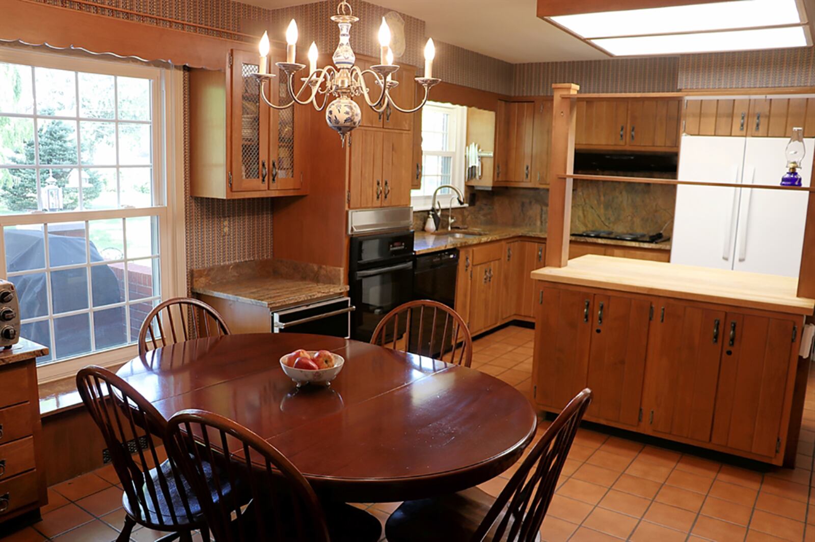 The eat-in kitchen has space for everything. Two countertops with drawers flank a window and have screen-accented display cabinets above. Granite countertops complement the cabinetry, which also includes a planning station. An island has a butcher-block countertop. CONTRIBUTED PHOTO BY KATHY TYLER