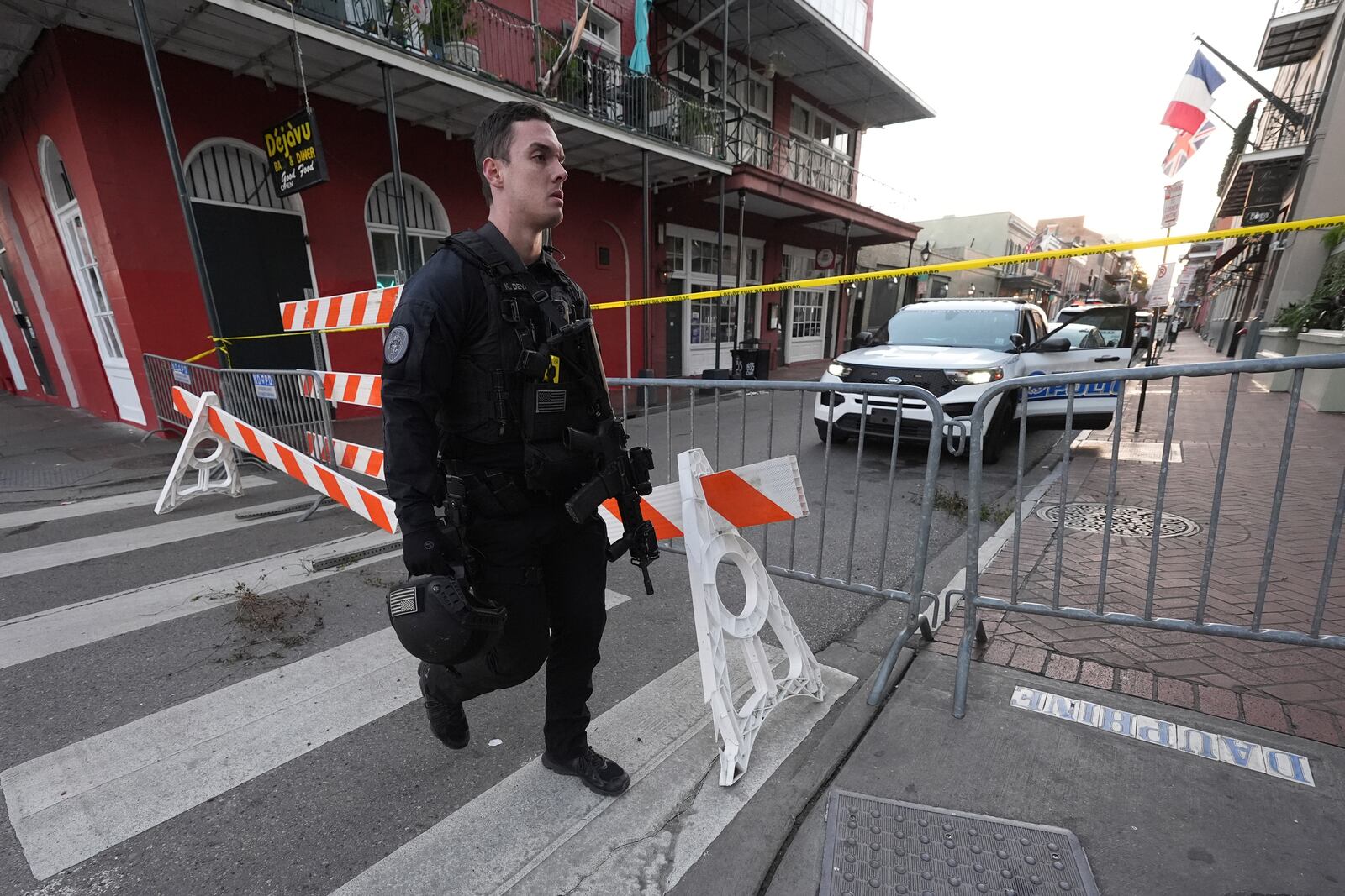 A member of the emergency services walks past a police barricade after a vehicle drove into a crowd on New Orleans' Canal and Bourbon Street, Wednesday Jan. 1, 2025. (AP Photo/Gerald Herbert)