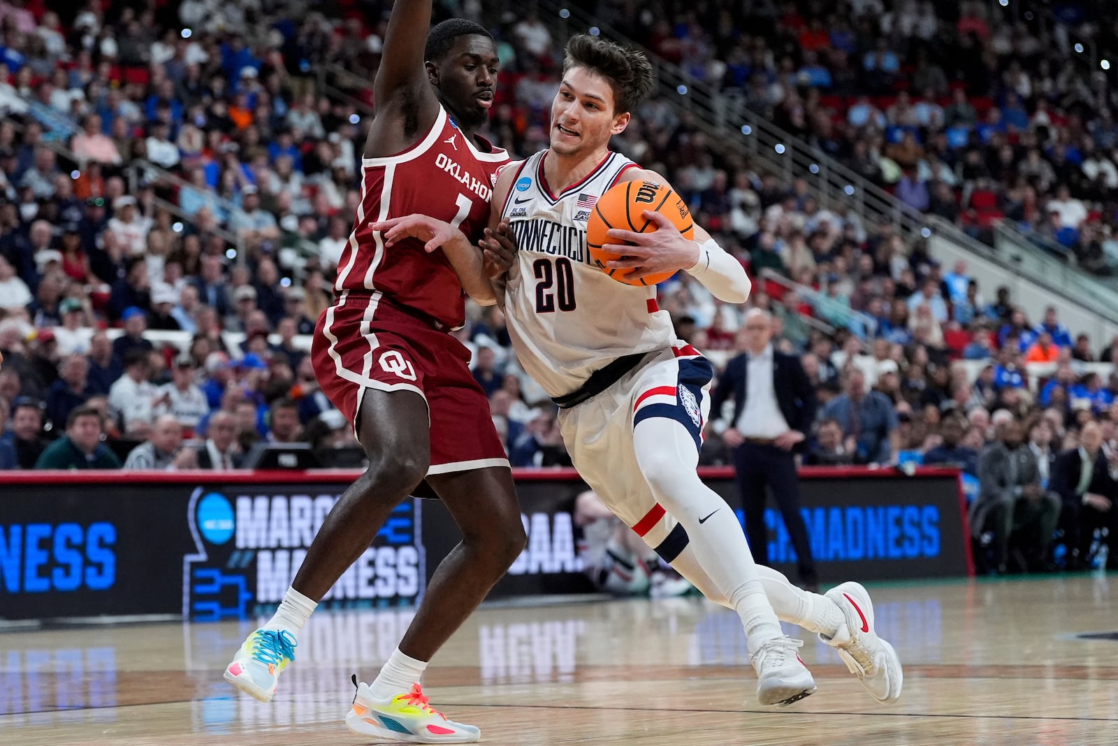 UConn forward Liam McNeeley (30) drives past Oklahoma guard Kobe Elvis (1) during the first half in the first round of the NCAA college basketball tournament, Friday, March 21, 2025, in Raleigh, N.C. (AP Photo/Stephanie Scarbrough)