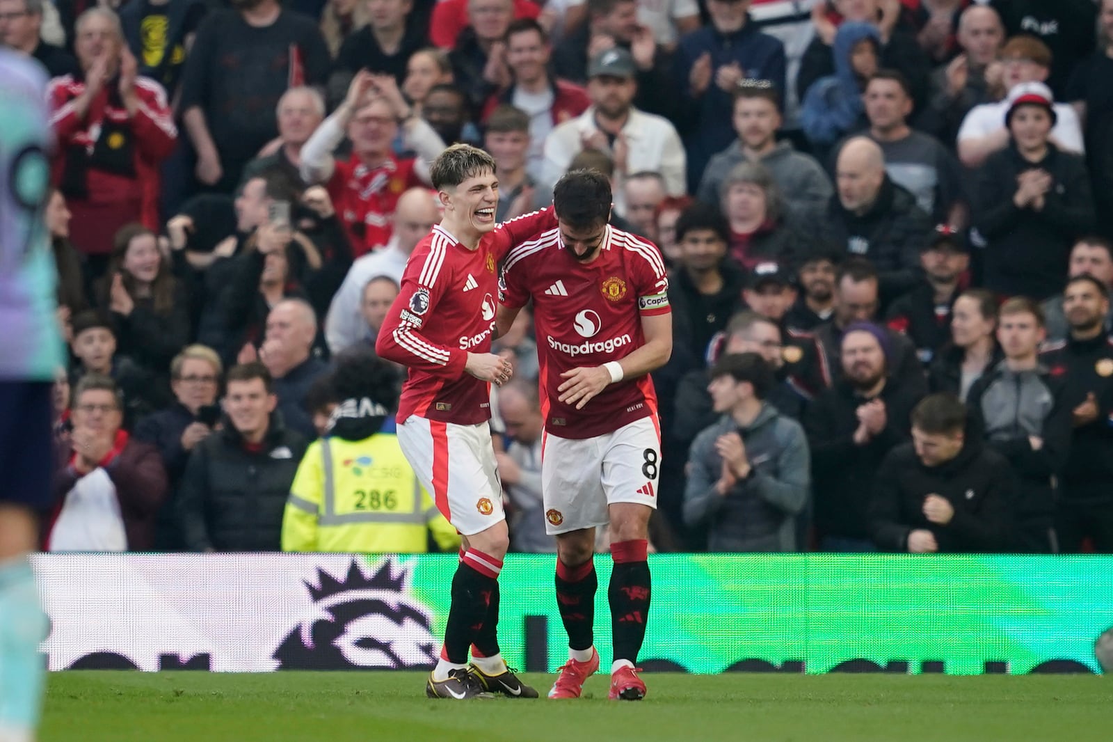 Manchester United's Bruno Fernandes, right, is congratulated by Alejandro Garnacho after scoring his side's opening goal during the English Premier League soccer match between Manchester United and Arsenal at Old Trafford stadium in Manchester, England, Sunday, March 9, 2025. (AP Photo/Dave Thompson)