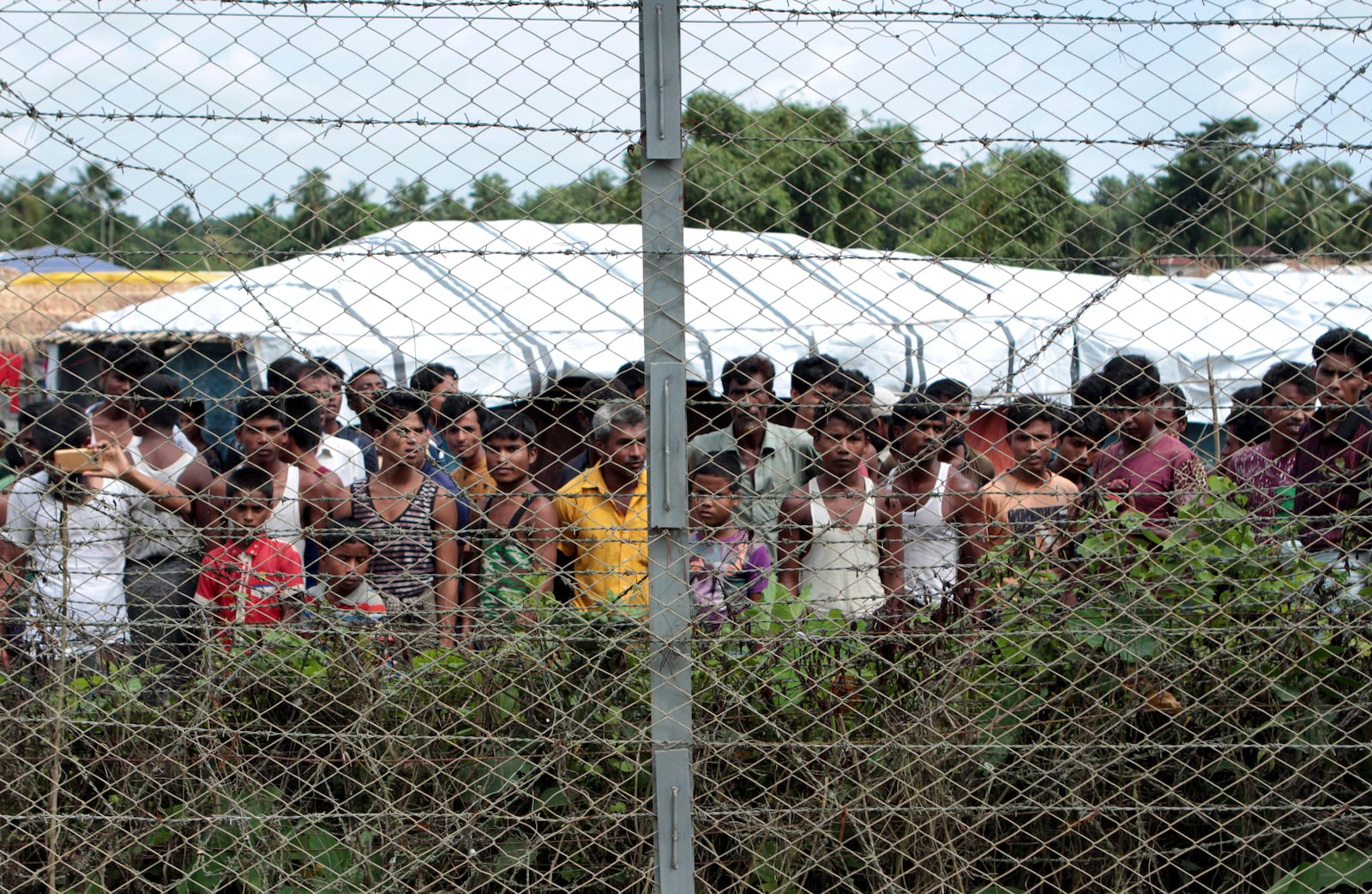 FILE - Rohingya refugees gather near a fence during a government organized media tour, to a no-man's land between Myanmar and Bangladesh, near Taungpyolatyar village, Maung Daw, northern Rakhine State, Myanmar, June 29, 2018. (AP Photo/Min Kyi Thein, File)