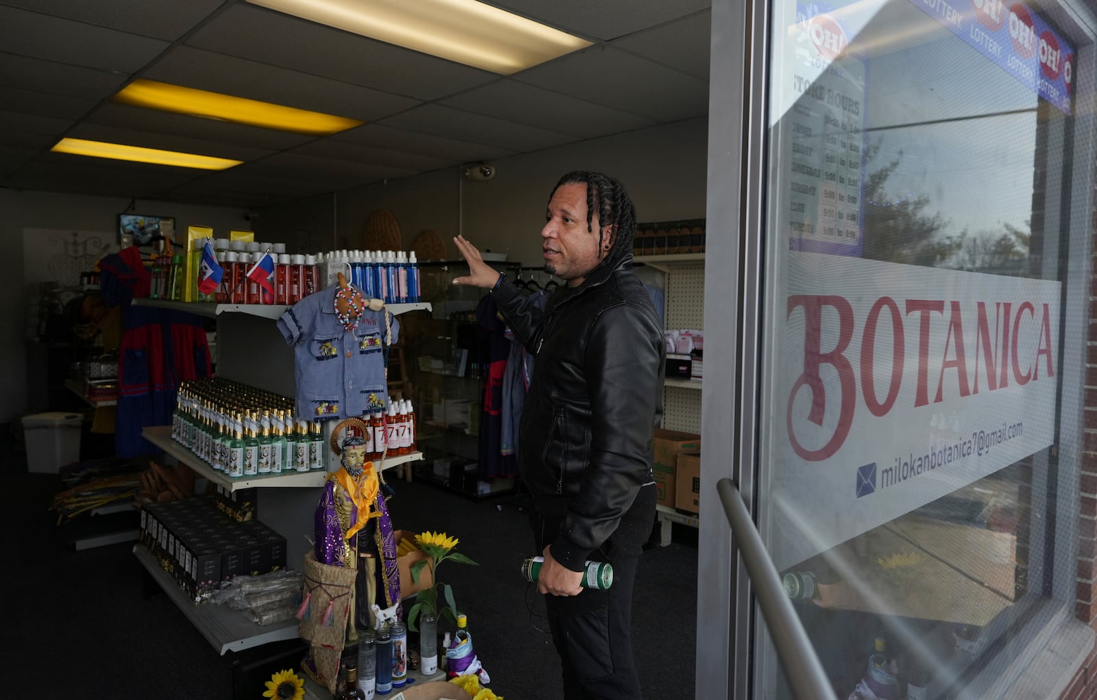 Jacob Payton talks to customers at the entrance of Milokan Botanica, his religious supply shop that sells Haitian spiritual and natural healing products, in Springfield, Ohio, Saturday, January 25, 2025. (AP Photo/Luis Andres Henao)