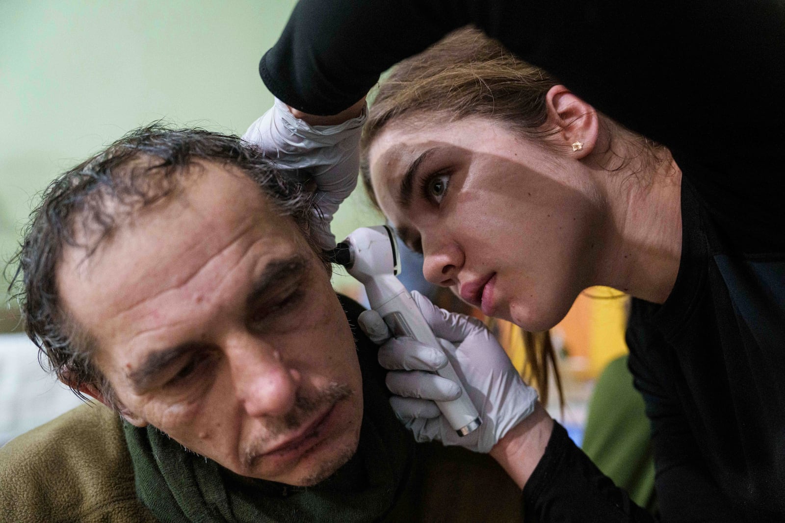 A medic checks the ear of an injured Ukrainian serviceman at Medical Service "Ulf" of the 108th Separate Battalion "Da Vinci Wolves" on Pokrovsk direction, Ukraine, Tuesday, Dec. 24, 2024. (AP Photo/Evgeniy Maloletka)