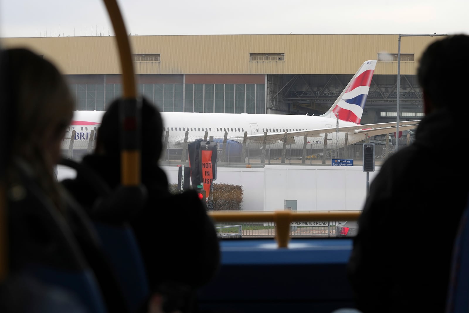 Passengers on a bus look at a parked plane as Britain's Heathrow Airport has closed for the full day Friday after an electrical substation fire knocked out its power, disrupting flights for hundreds of thousands of passengers at one of Europe's biggest travel hubs in London, Friday, March 21, 2025.(AP Photo/Kin Cheung)