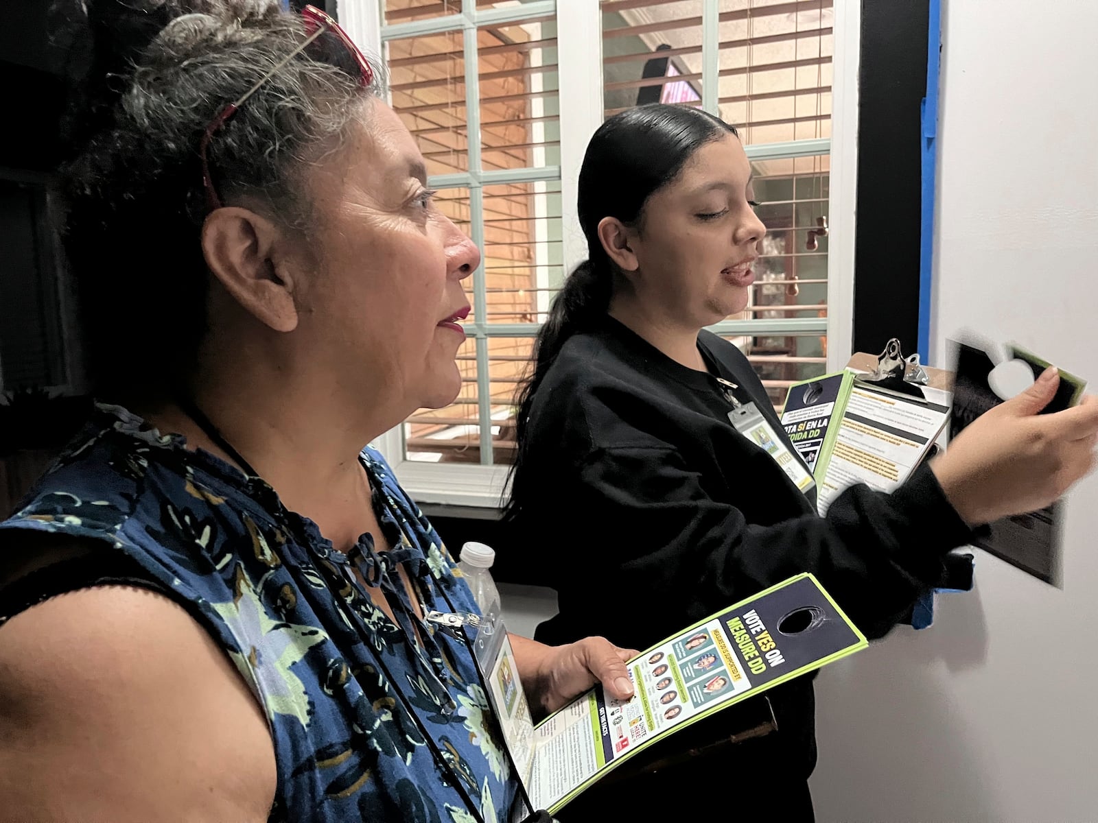 FILE - Genesis Lopez, 21, and her mother Nancy Morales, 51, left, speak with residents of a Santa Ana neighborhood on Wednesday, Oct. 23, 2024, about Measure DD, which would allow noncitizens to vote in local elections. (AP Photo/Jaimie Ding, File)