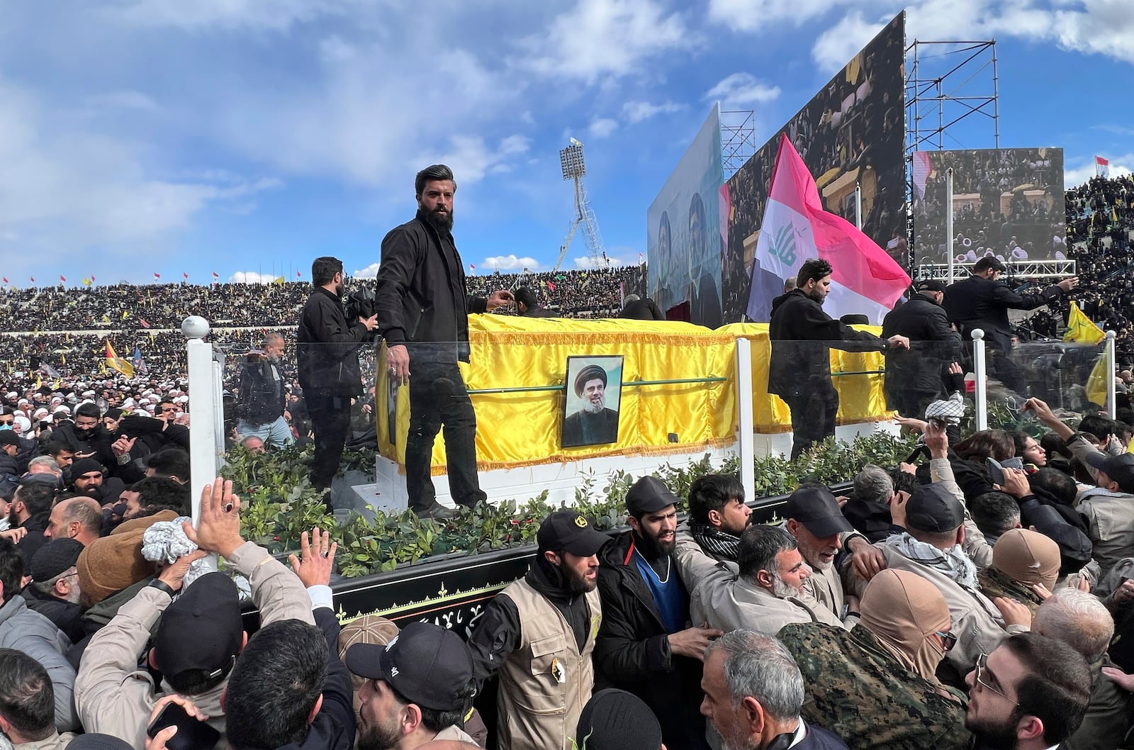 A trailer carrying the coffins containing the bodies of Hezbollah's former leader Hassan Nasrallah and his cousin and successor Hashem Safieddine drives through the crowd at the beginning of a funeral procession in the Sports City Stadium in Beirut, Lebanon, Sunday, Feb. 23, 2025. (AP Photo/Hussein Malla)