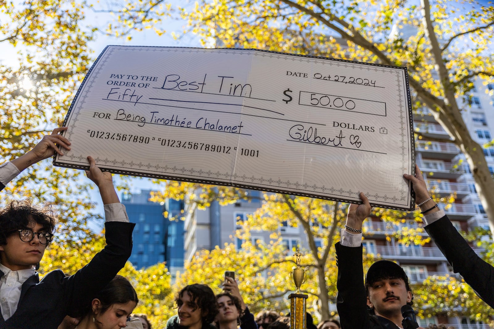 A giant cheque for the prize money is held aloft at the Timothee Chalamet lookalike contest near Washington Square Park, Sunday, Oct. 27, 2024, in New York. (AP Photo/Stefan Jeremiah)