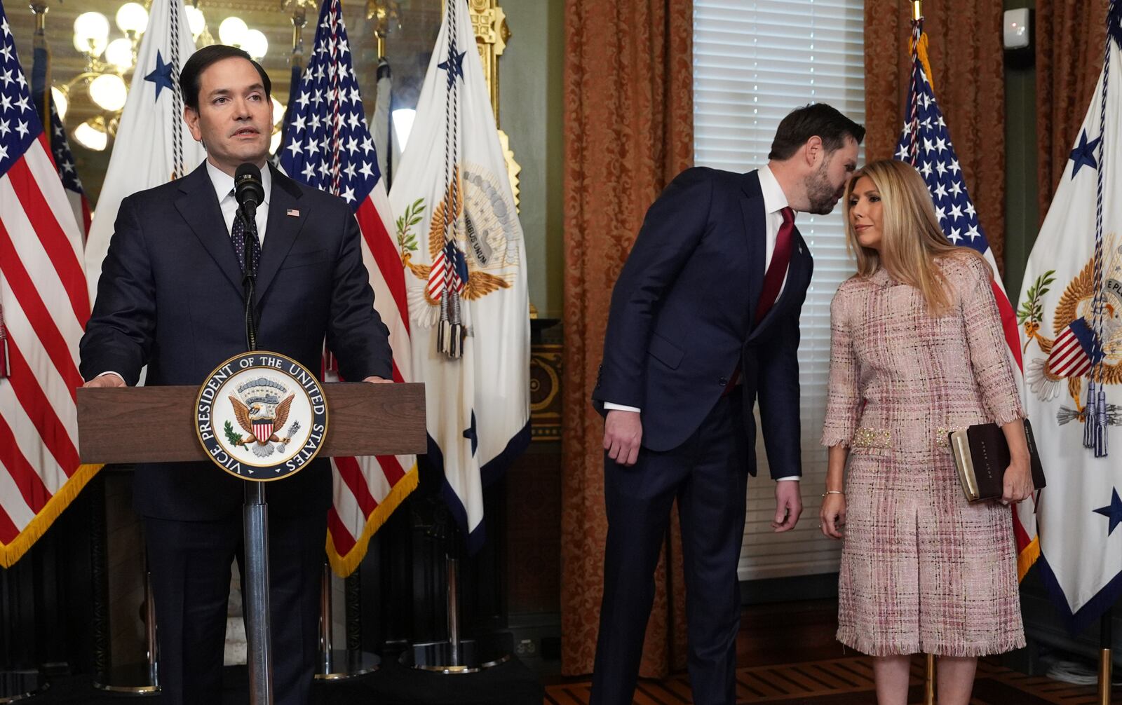 Secretary of State Marco Rubio speaks after being sworn in by Vice President JD Vance in the Vice Presidential Ceremonial Office in the Eisenhower Executive Office Building on the White House campus, Tuesday, Jan. 21, 2025, in Washington, as Vance whispers to his wife, Jeanette Rubio, right. (AP Photo/Evan Vucci)