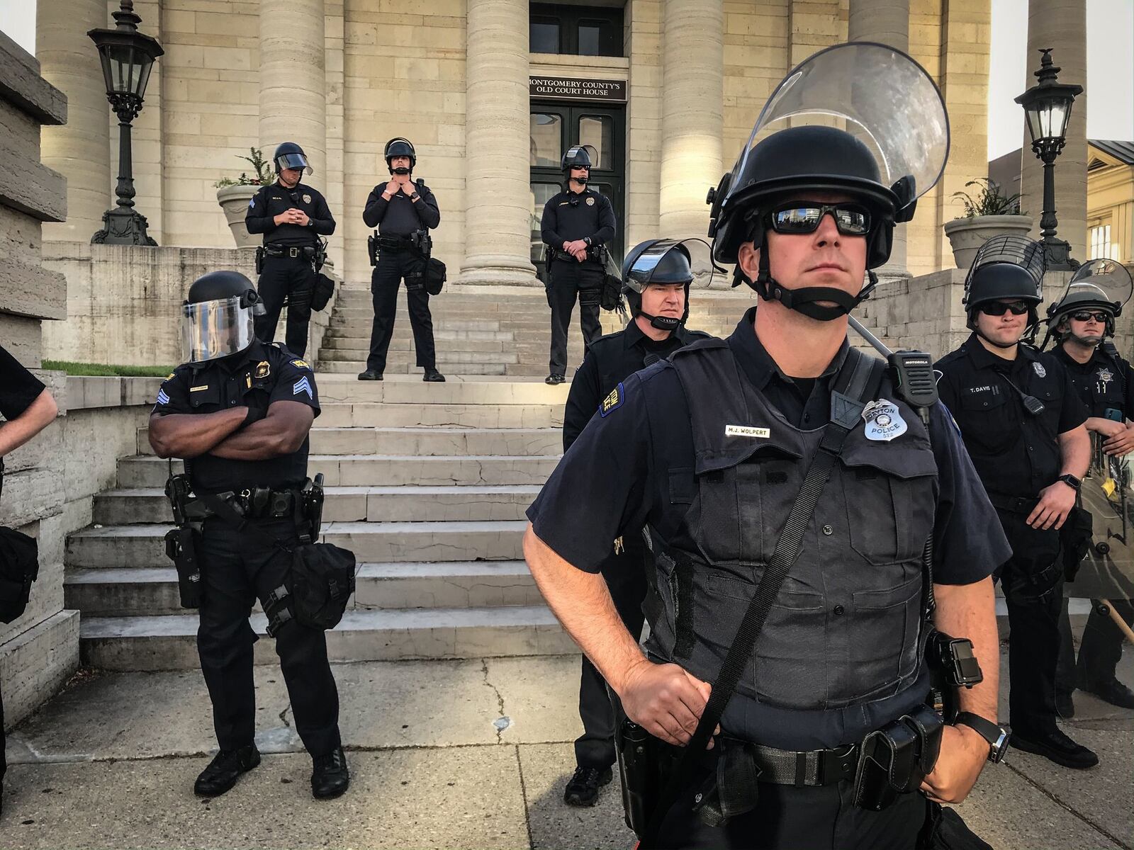 Police stand on courthouse steps when curfew went into effect Sunday night in downtown Dayton. JIM NOELKER / STAFF