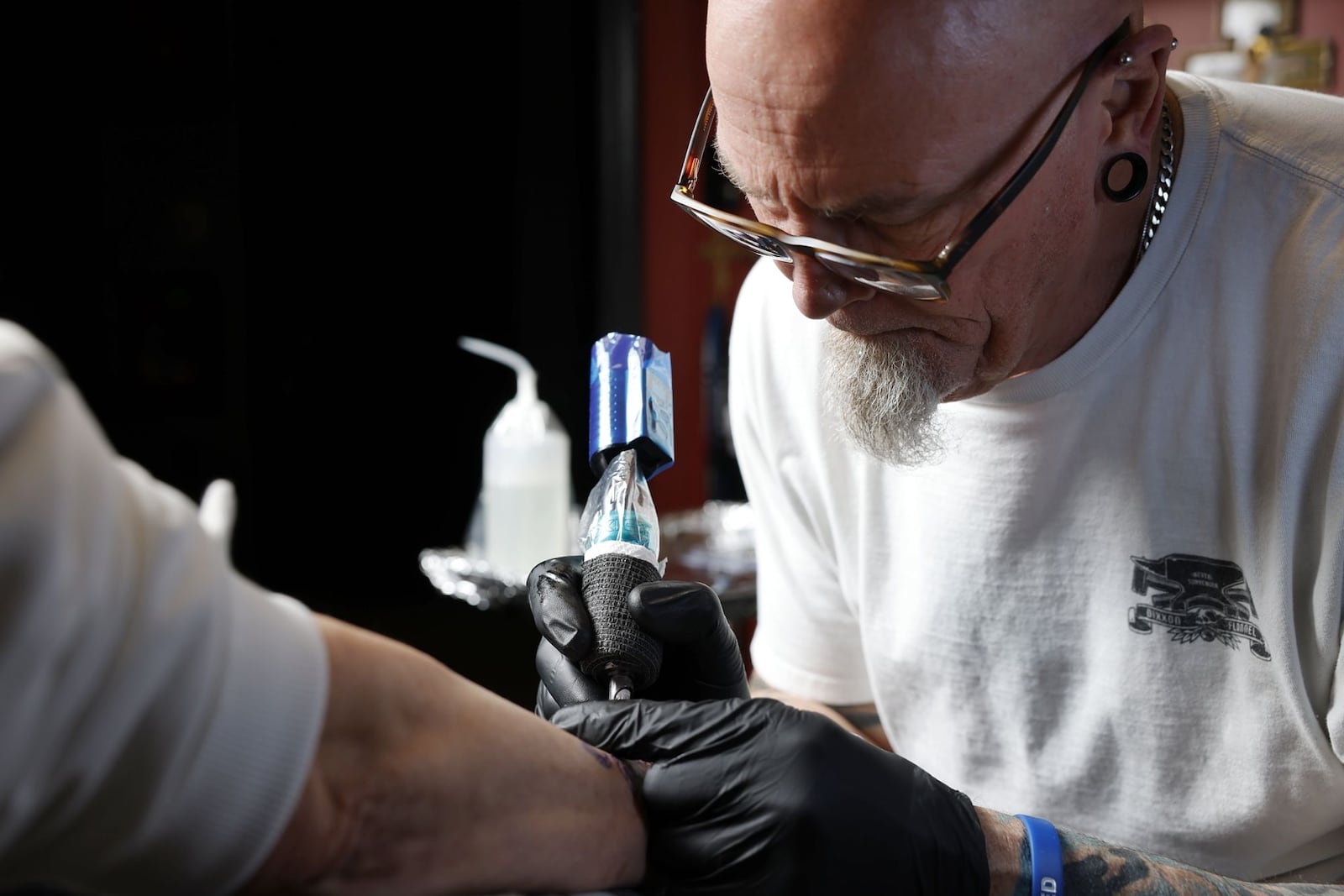 Tattoo artist Archie Payne works on customer at Immortal Canvas Tattoo & Piercing Friday, Feb. 28, 2025, on Ohio 4 in Fairfield Twp. Tattoo shop owner Carter Moore, who owns multiple businesses in Hamilton, would like to relocate his Fairfield Twp. shop closer to his other businesses. NICK GRAHAM/STAFF