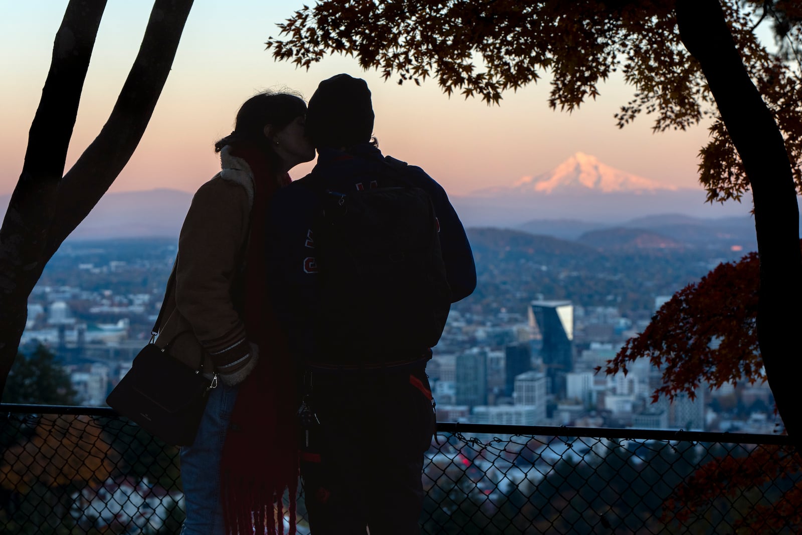 With Mount Hood in the background, Tara Bellido kisses Seth Herzog, both of Baltimore, as the sun sets on Wednesday, Nov. 6, 2024, in Portland, Ore. (AP Photo/Jenny Kane)