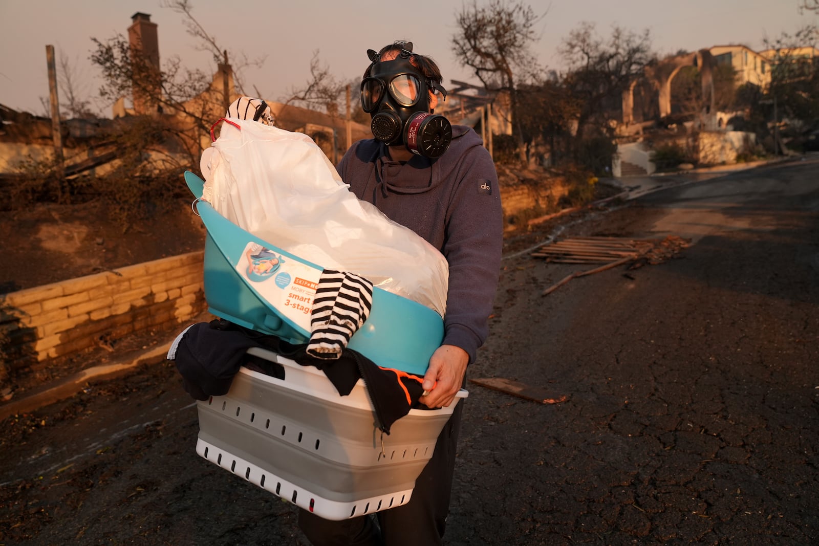 FILE - Josh Lederer wears a mask to protect him from fumes as he retrieves his children's clothes from his fire-ravaged property in the aftermath of the Palisades Fire in the Pacific Palisades neighborhood of Los Angeles, Thursday, Jan. 9, 2025. (AP Photo/Jae C. Hong, File)