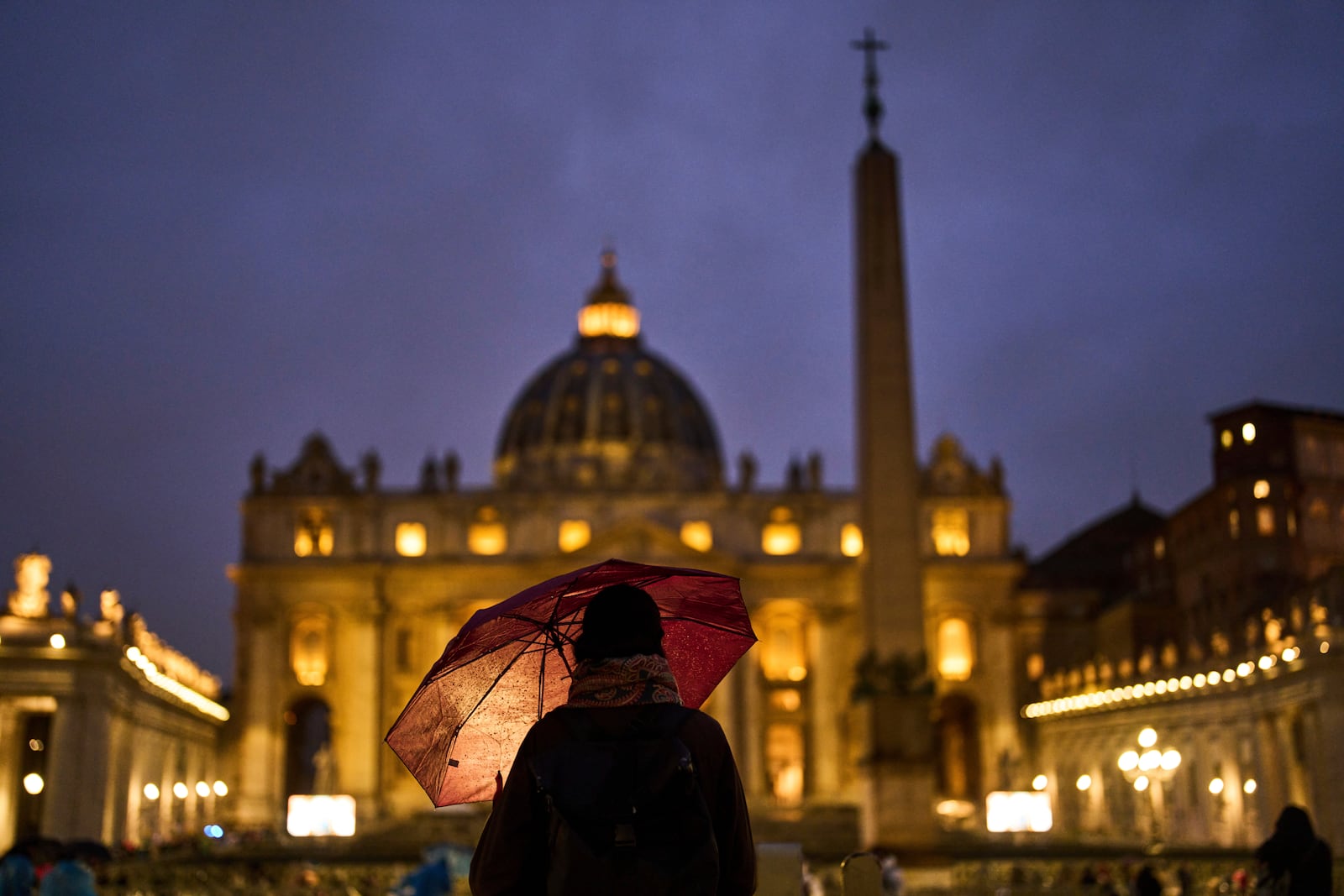 A woman shelters against the rain as she follows a live broadcasted Rosary prayer for Pope Francis, in St. Peter's Square at the Vatican, Wednesday, March 12, 2025. (AP Photo/Francisco Seco)