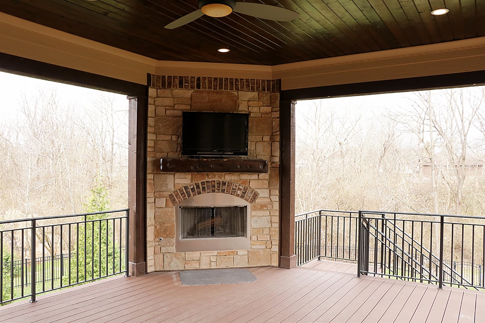 A stone, gas fireplace has brick accents and a wood-beam mantel with media outlets above enhance the covered back deck. CONTRIBUTED PHOTO BY KATHY TYLER