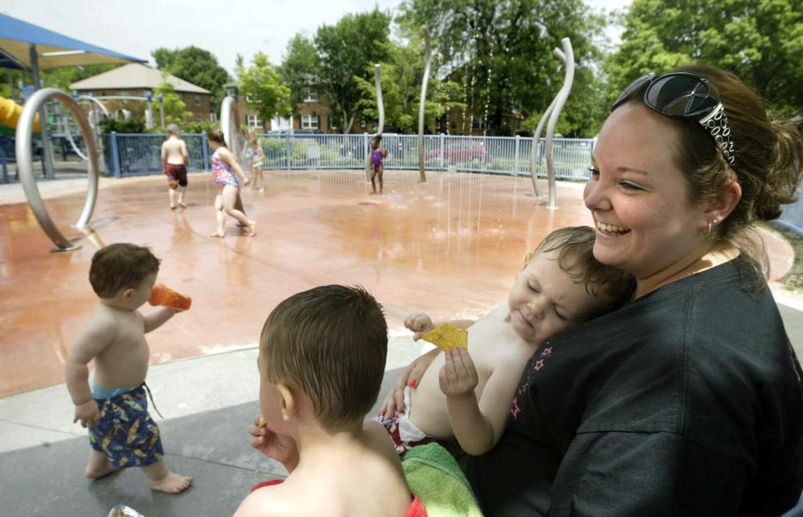 Kristina Rader of Kettering and her two sons Trenton, 4 and Alex, 2, take a break from fun in the spray park at Orchardly Park in Oakwood Thursday June 2. As of April 1, the state requires local health agencies to inspect and license splash pads to make sure the water is filtered and treated. Rader said she thought monitoring the parks was " a good idea to make sure kids are healthy."