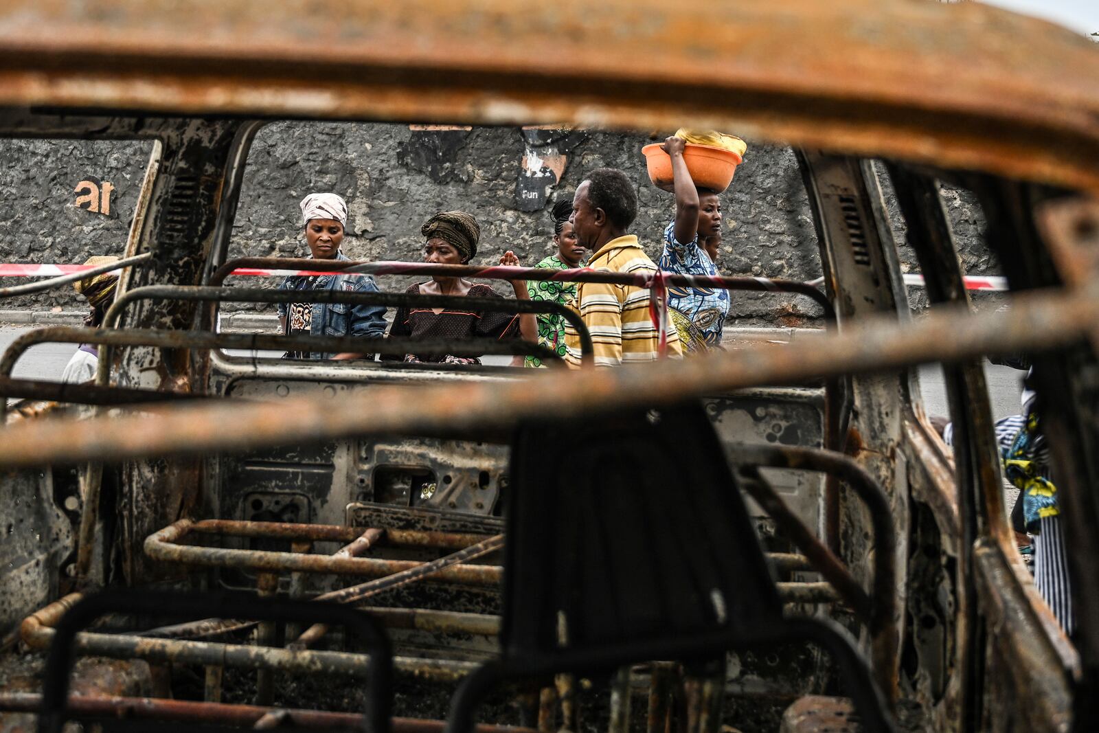 Residents walk by charred vehicles in Goma, Democratic republic of the Congo, Friday, Jan. 31, 2025. (AP Photo/Moses Sawasawa)