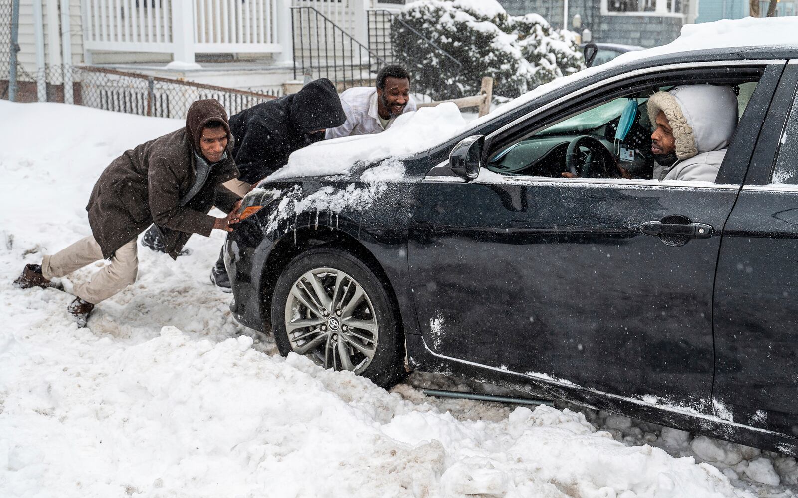 Ahmed Yasir steps on the gas while others push and rock his car was stuck in a driveway in Lewiston, Maine, Sunday, Feb. 16, 2025. (Russ Dillingham/Sun Journal via AP)