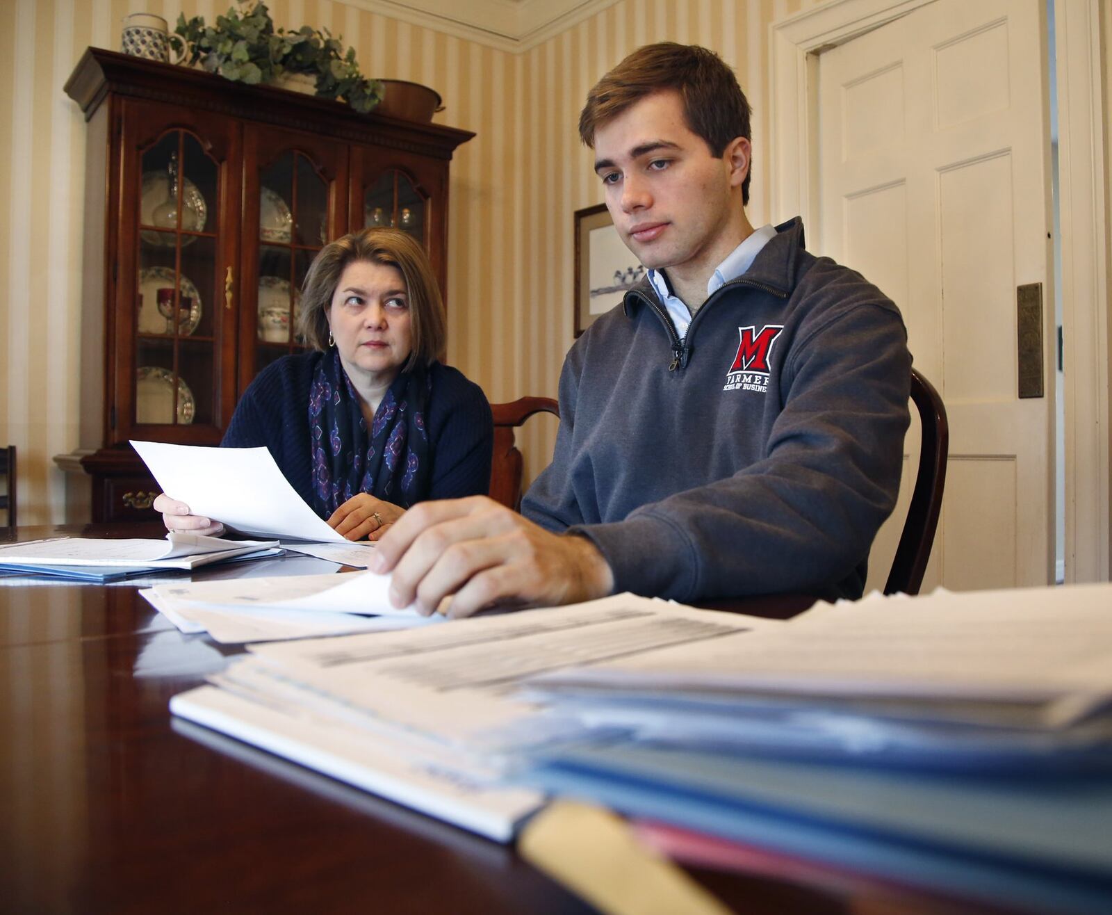 Reid Rupp, 21, right, looks over a pile of medical bills with his mother Lisa Rupp. Rupp was riding his bike to class at Miami University when he suffered a severe bicycle accident that required emergency facial reconstructive surgery for a broken jaw and facial bones. The plastic surgeon that performed the work was not in network with the hospital and Rupp is now stuck with more than $17,000 owed to the surgeon. TY GREENLEES / STAFF